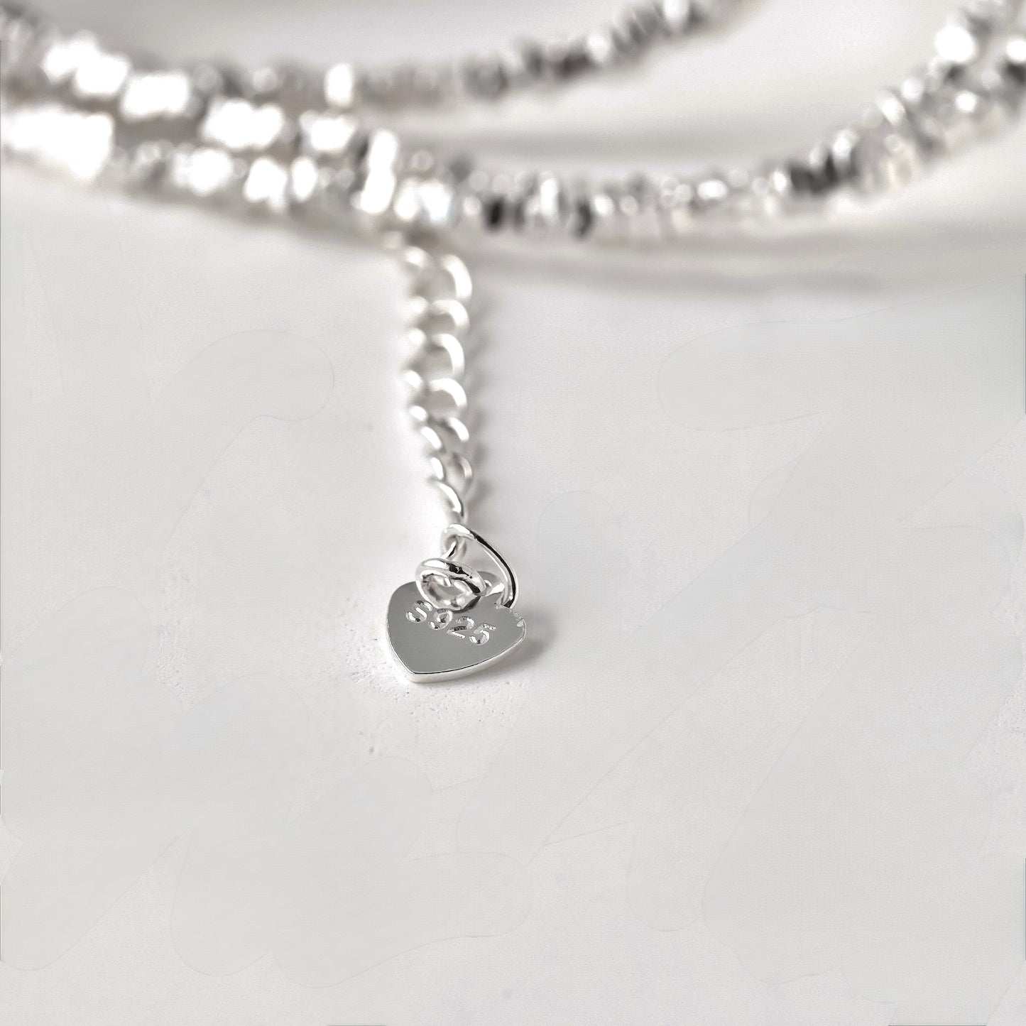 close-up view of heart shaped tag with S925 stamp at the end of the extender chain of the silver necklace