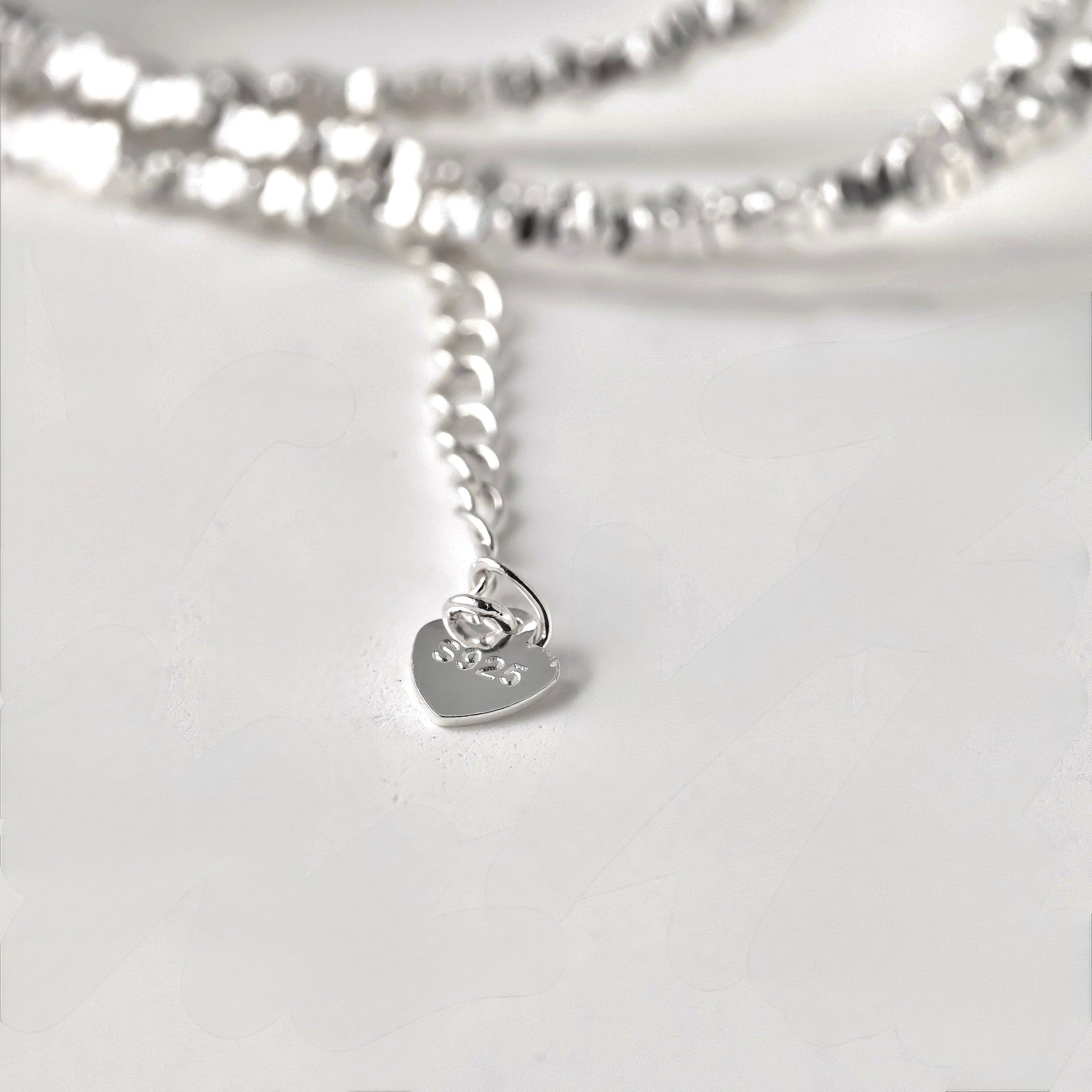 close-up view of heart shaped tag with S925 stamp at the end of the extender chain of the silver necklace