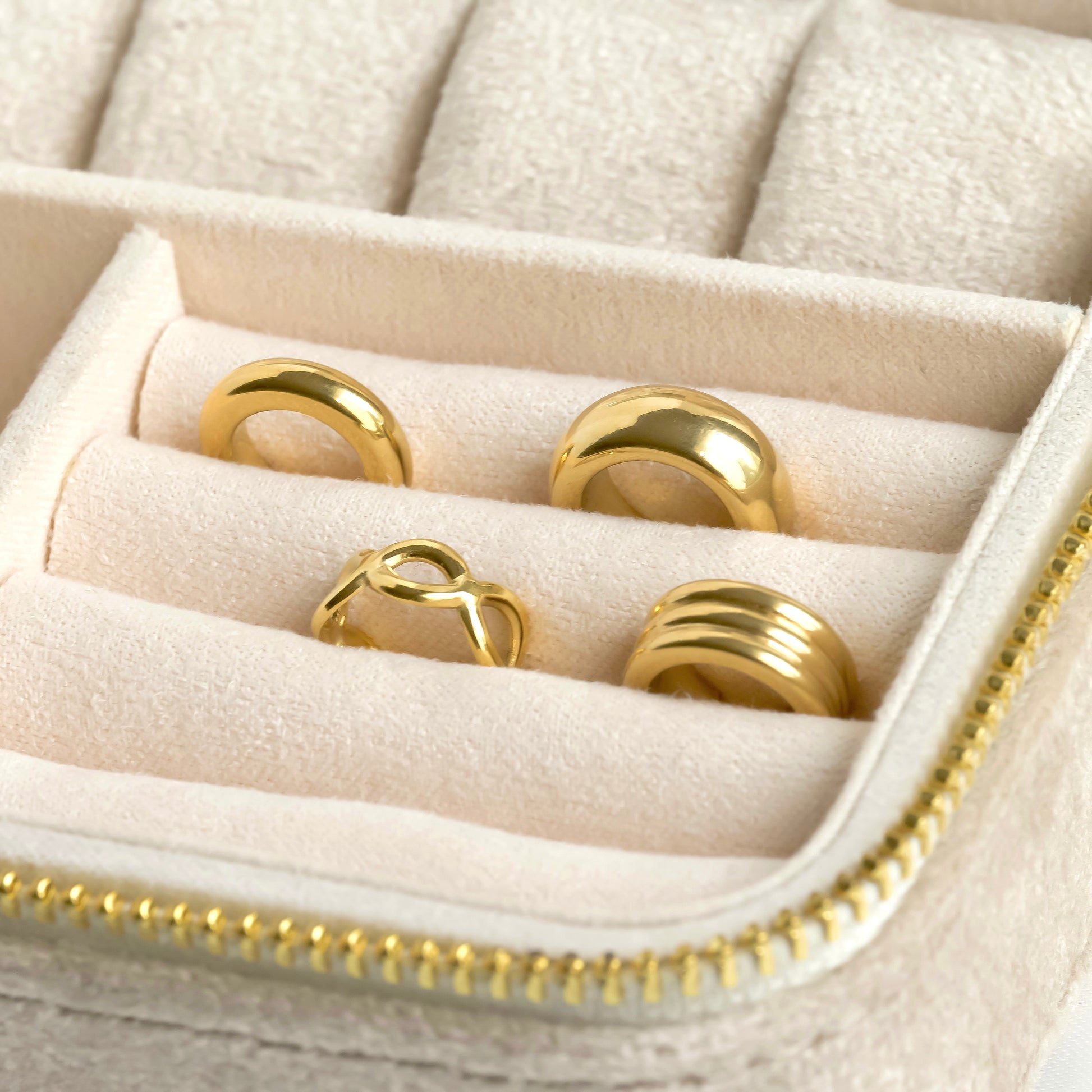 Set of gold ear cuffs in a jewelry box with beige interior