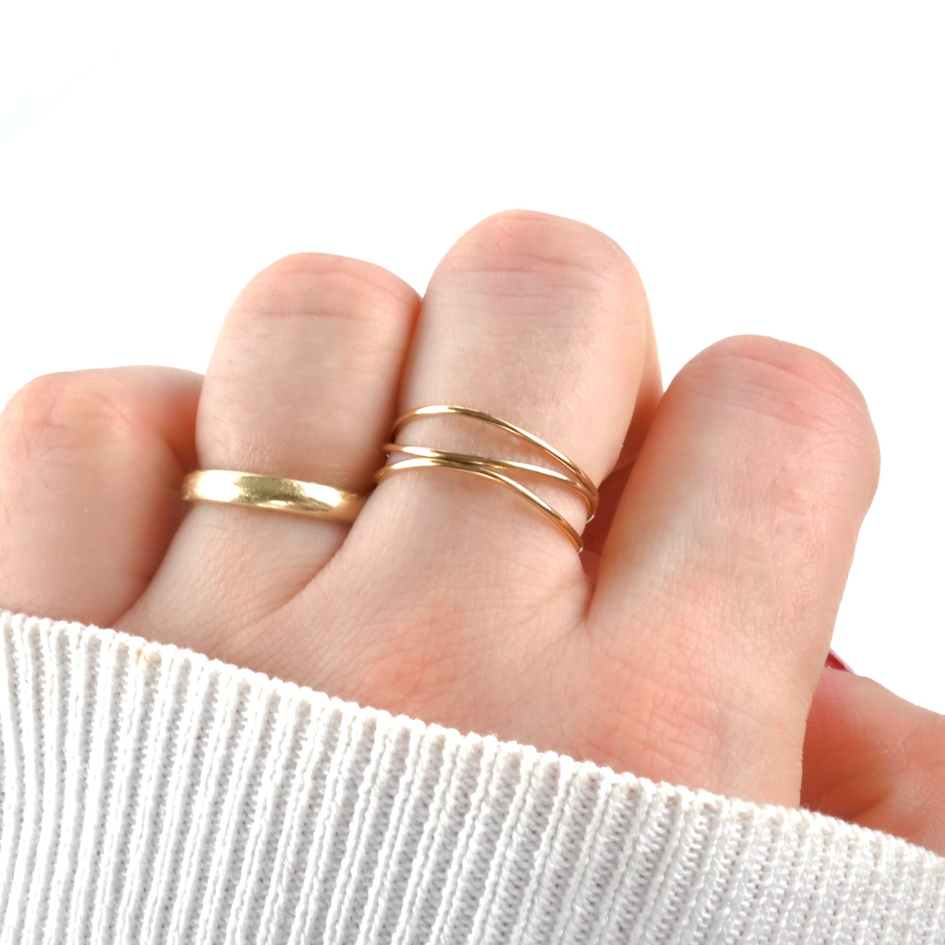 Layered gold ring on a finger with a white sleeve background