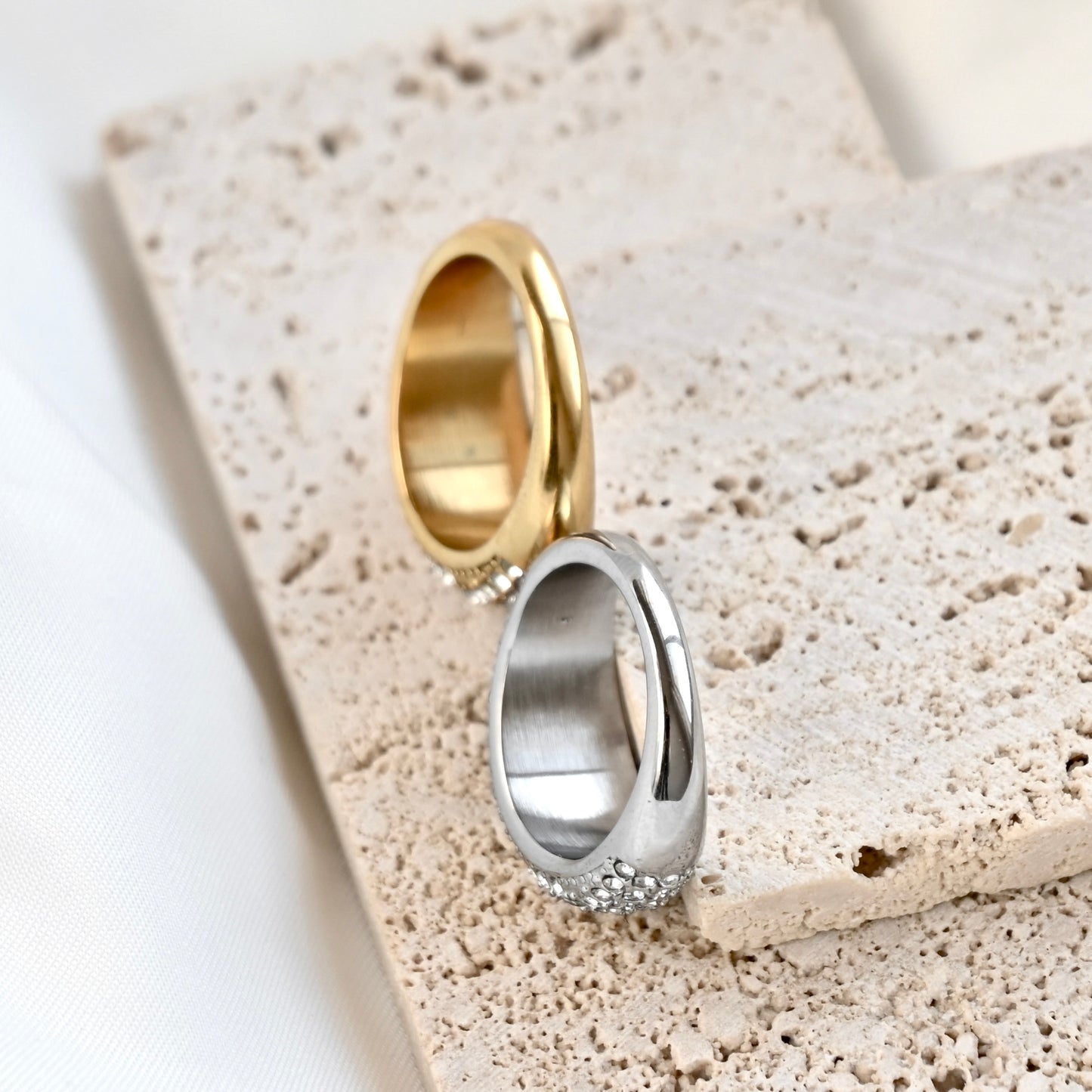 top view of the back thinner side of gold and silver dome rings on a textured stone surface