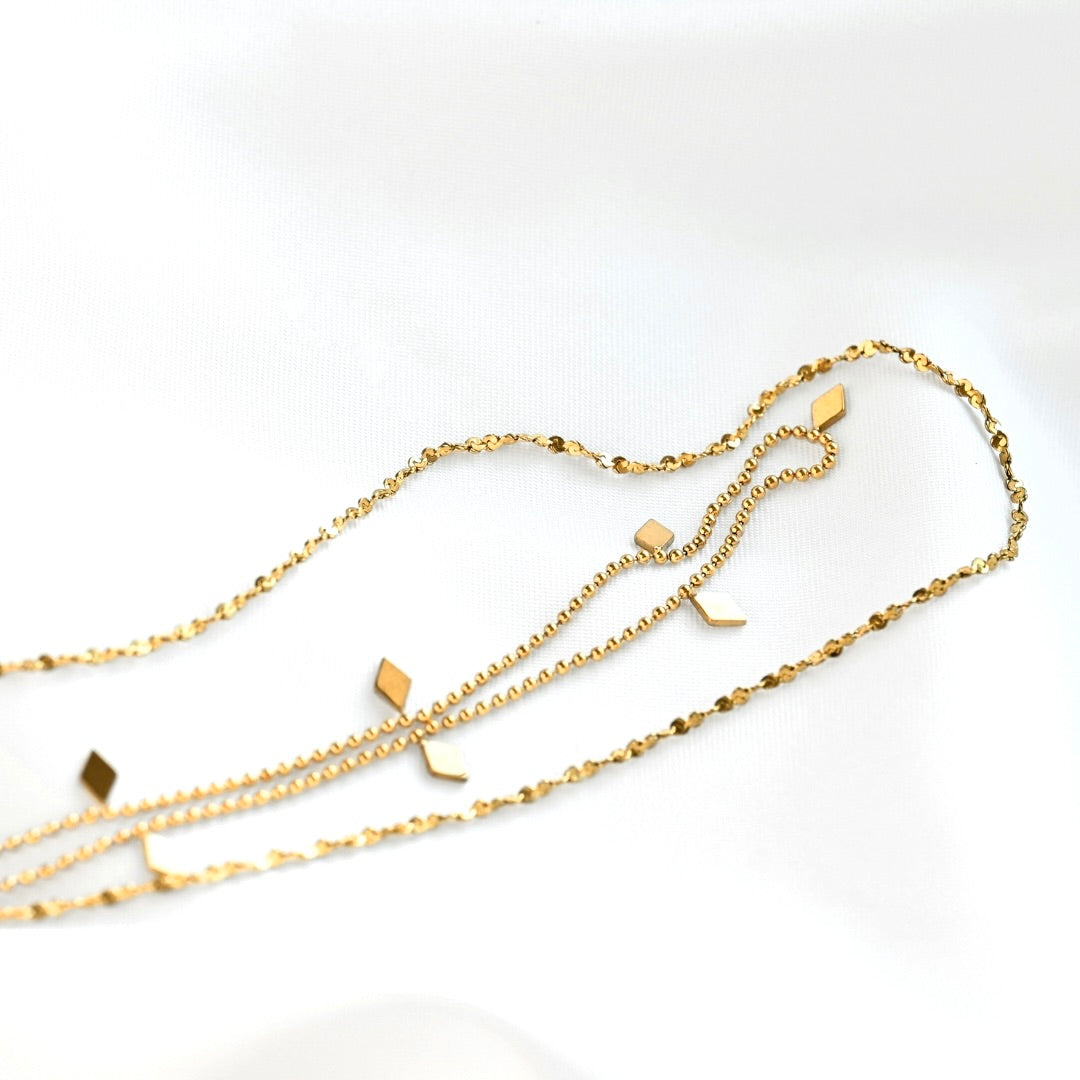 Layered gold chain necklace on a white background