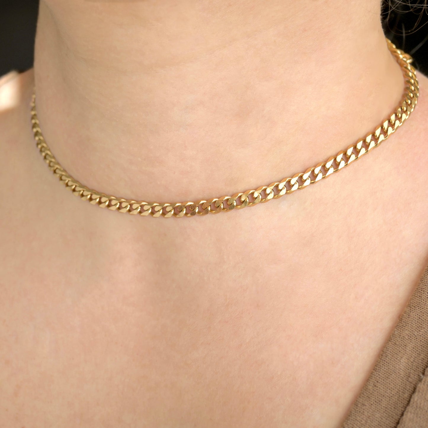 Thick gold cuban chain choker necklace on a person's neck