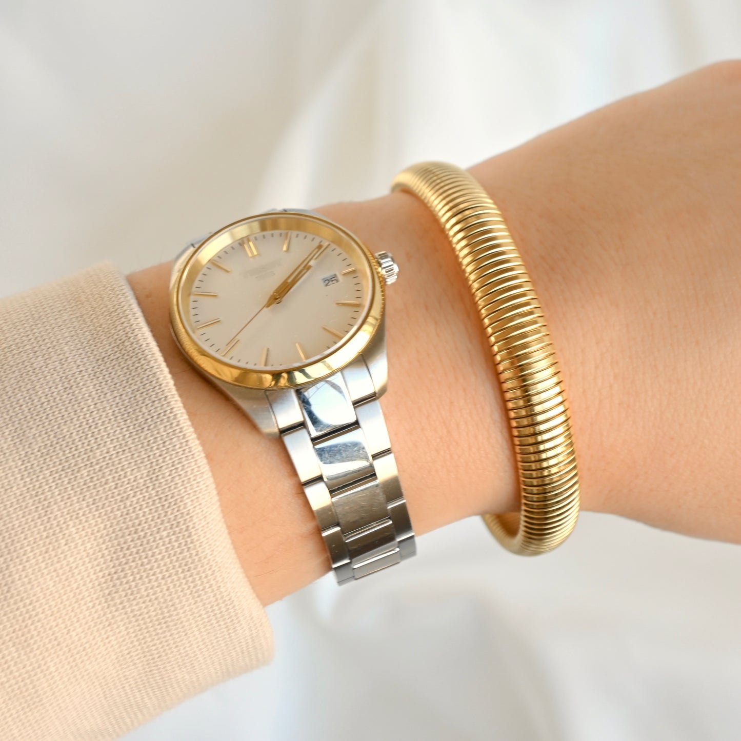10mm tubogas bangle stacked with a two-tone watch on a wrist against a white background