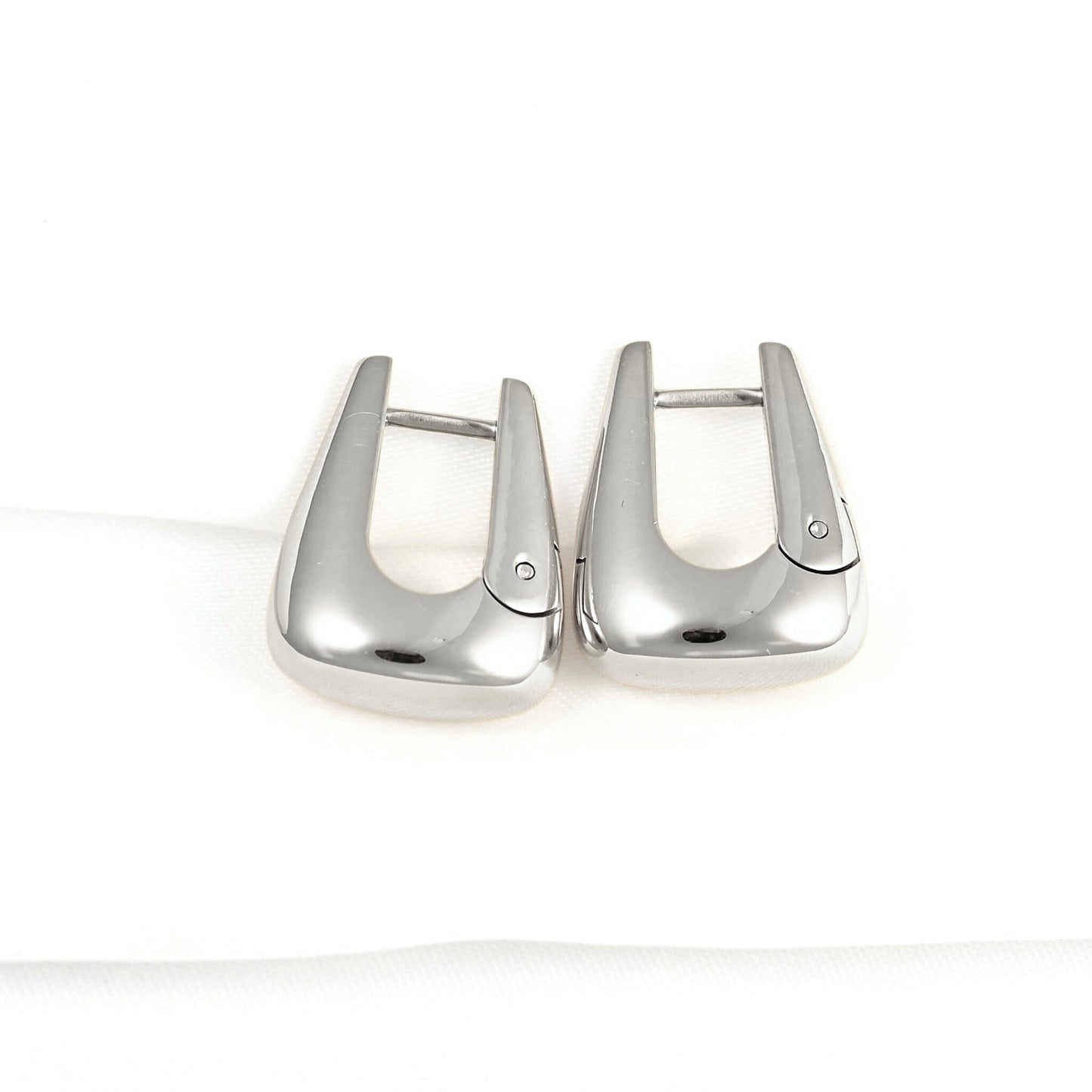 A pair of polished silver-toned metal lobster clasp earrings on a clean white background.