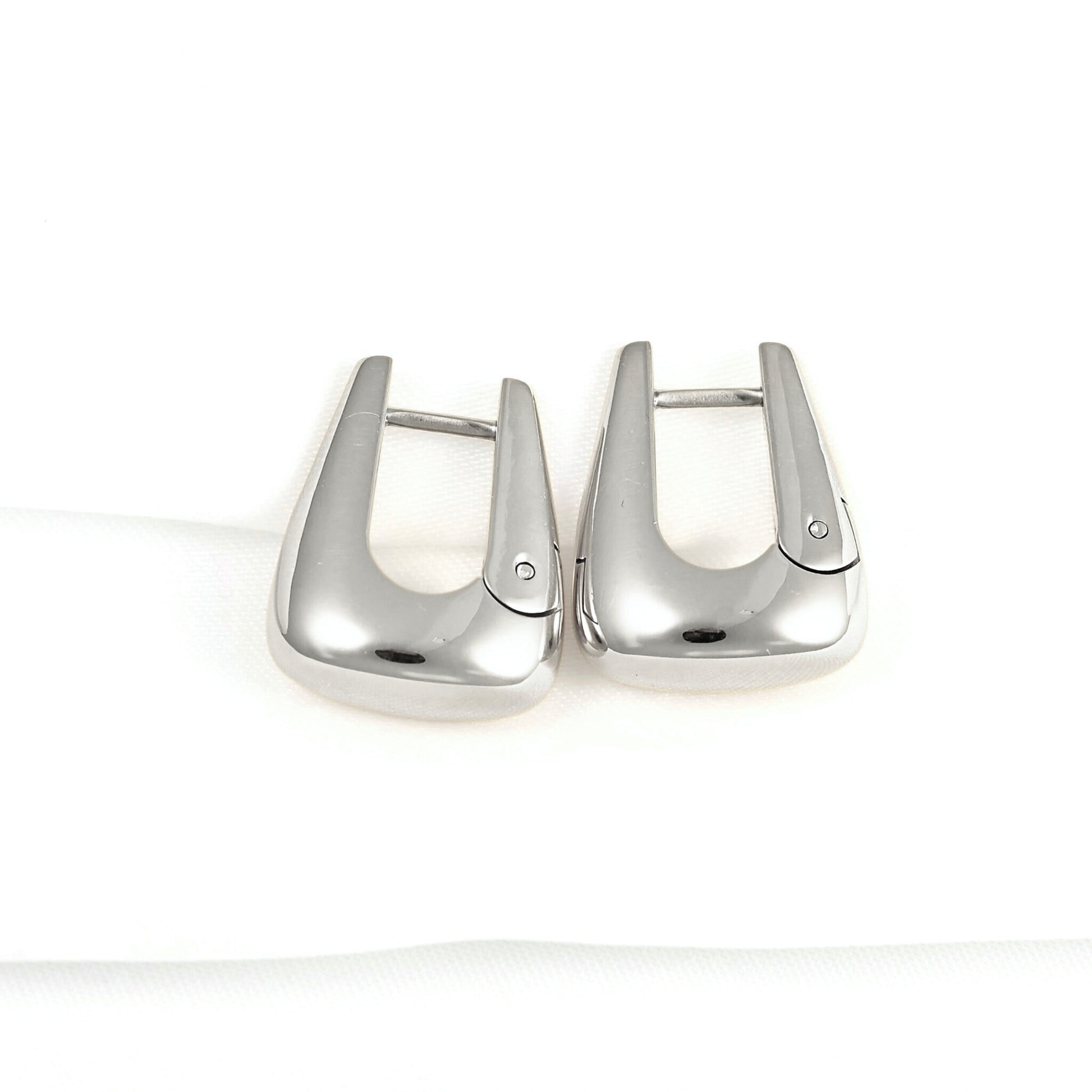 A pair of polished silver-toned metal lobster clasp earrings on a clean white background.