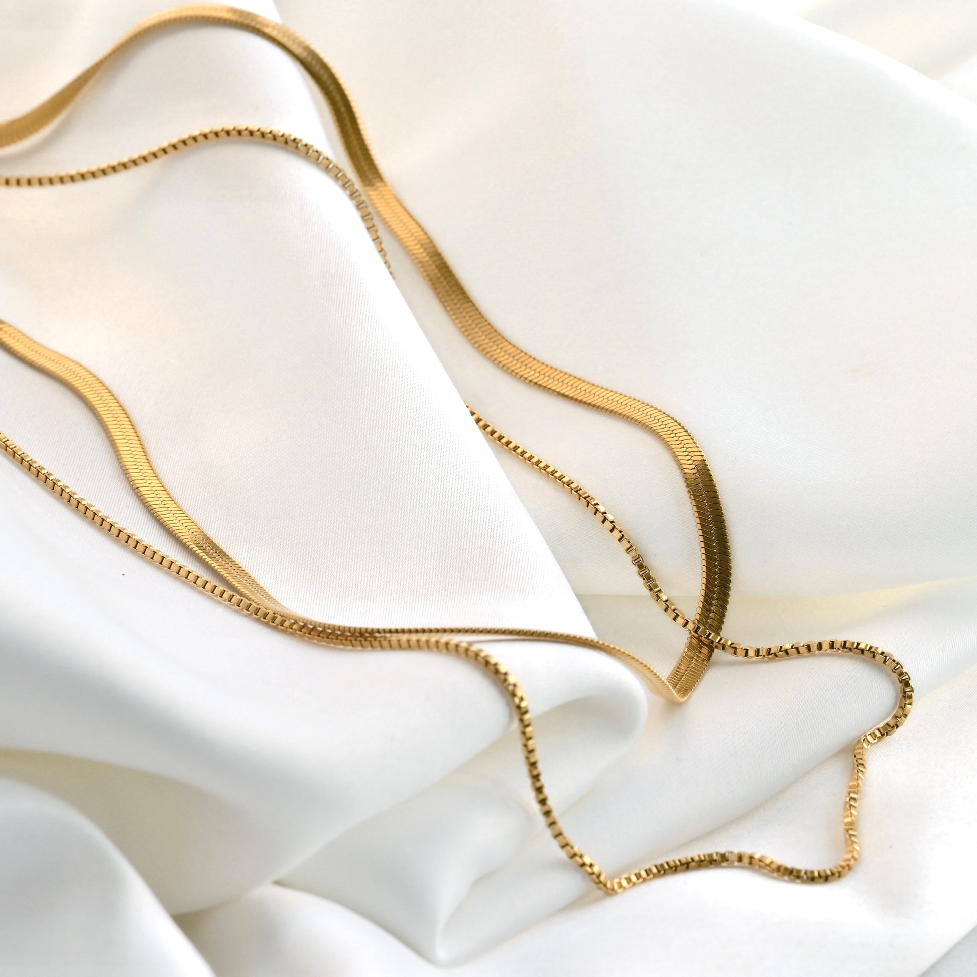Gold chain necklace on a white fabric background