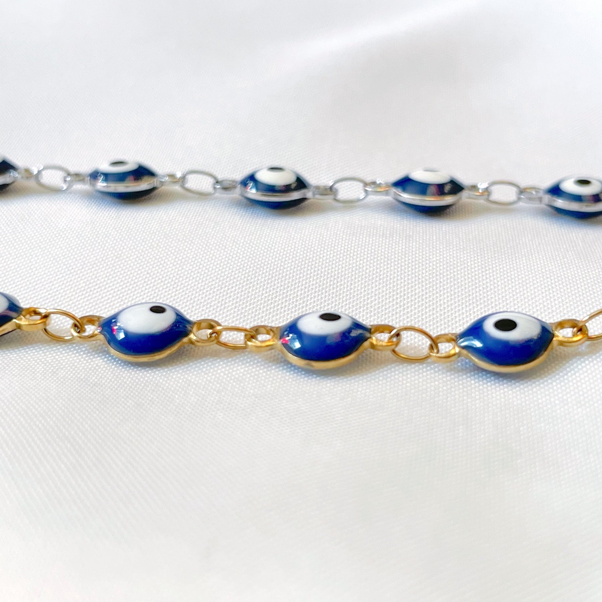 Gold and silver ev il eye connector beads on a white fabric background