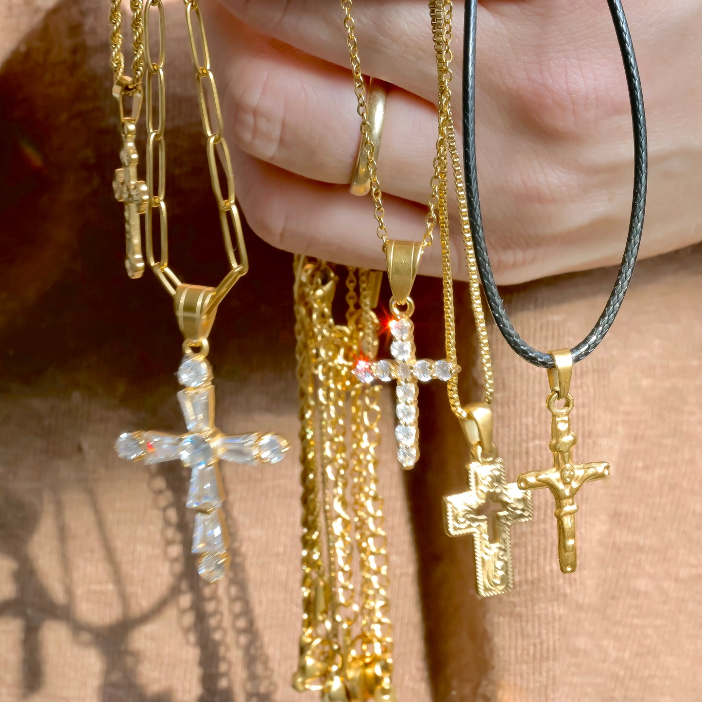 Gold cross necklaces held by a hand against a blurred background