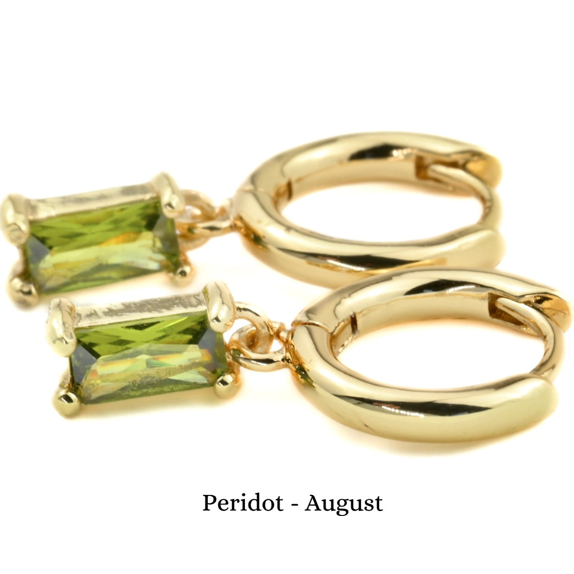Gold huggie hoop earrings with peridot charm on a white background