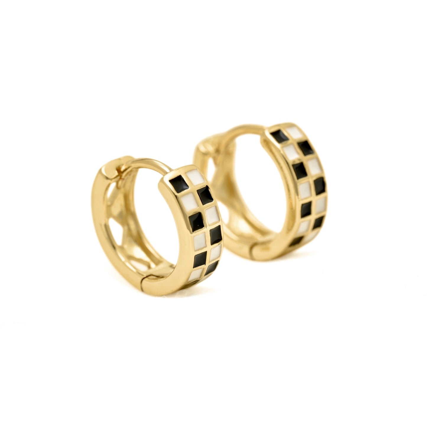 A pair of gold huggie hoop earrings featuring a checkered pattern of black and white square inlays, set against a plain white background.