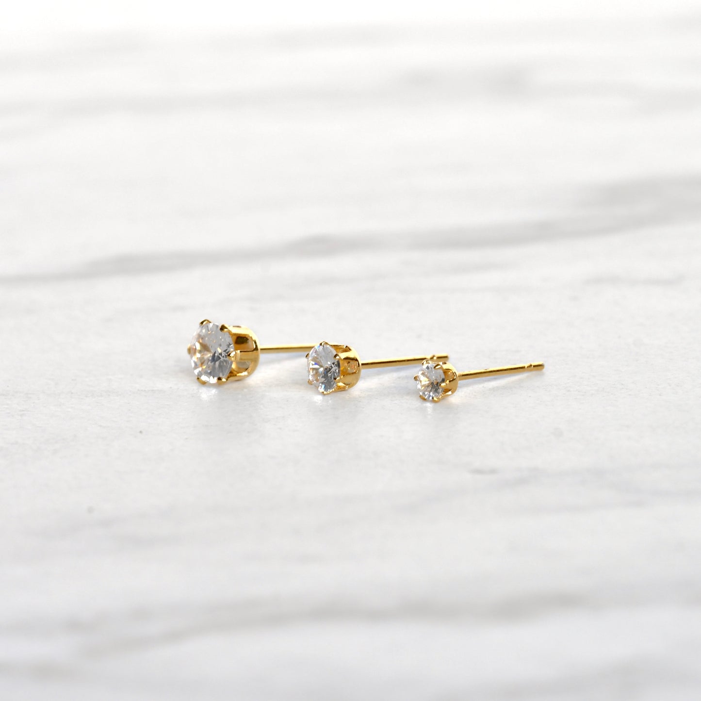Close-up side view of gold CZ studs in a basket setting  secured with six prongs