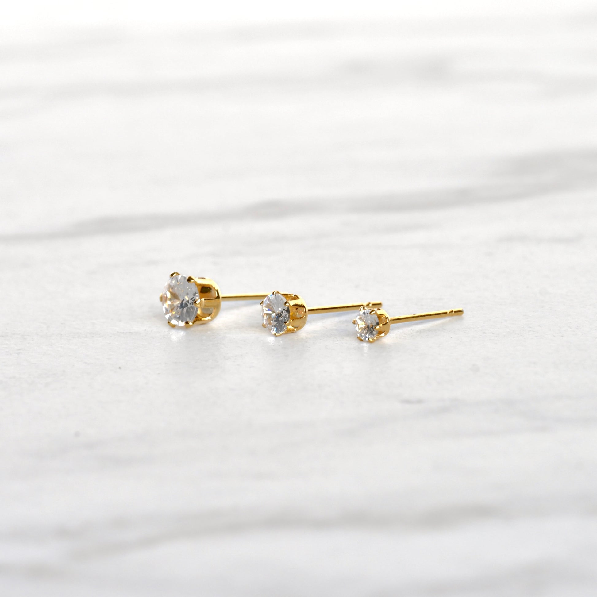 Close-up side view of gold CZ studs in a basket setting  secured with six prongs