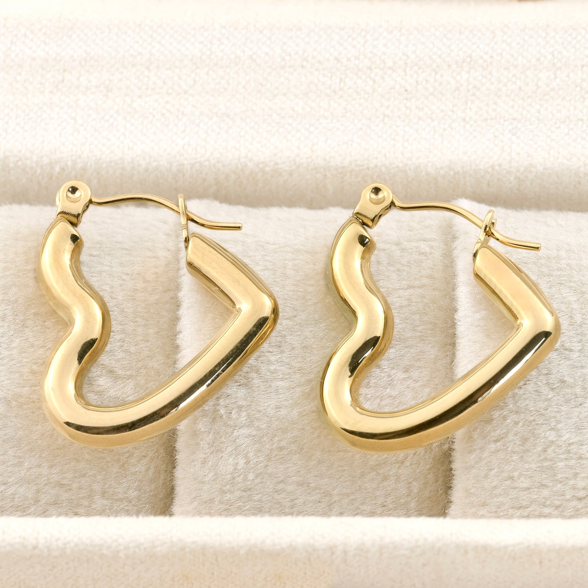 Gold hoop earrings on a textured beige surface