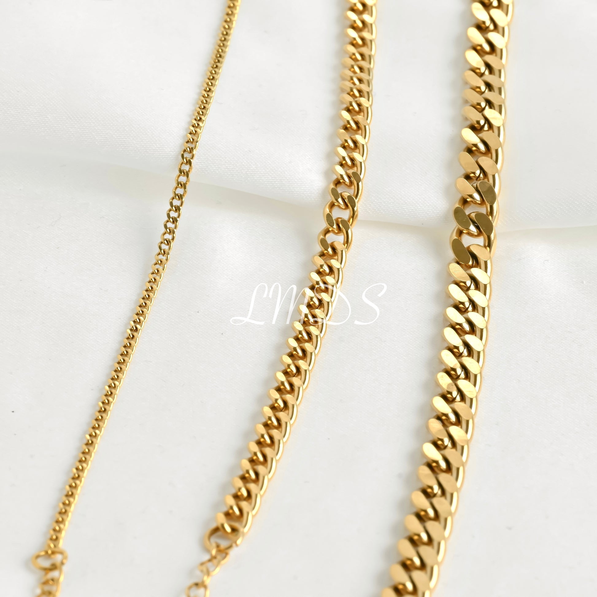 Three gold cuban chains of different widths on a white background