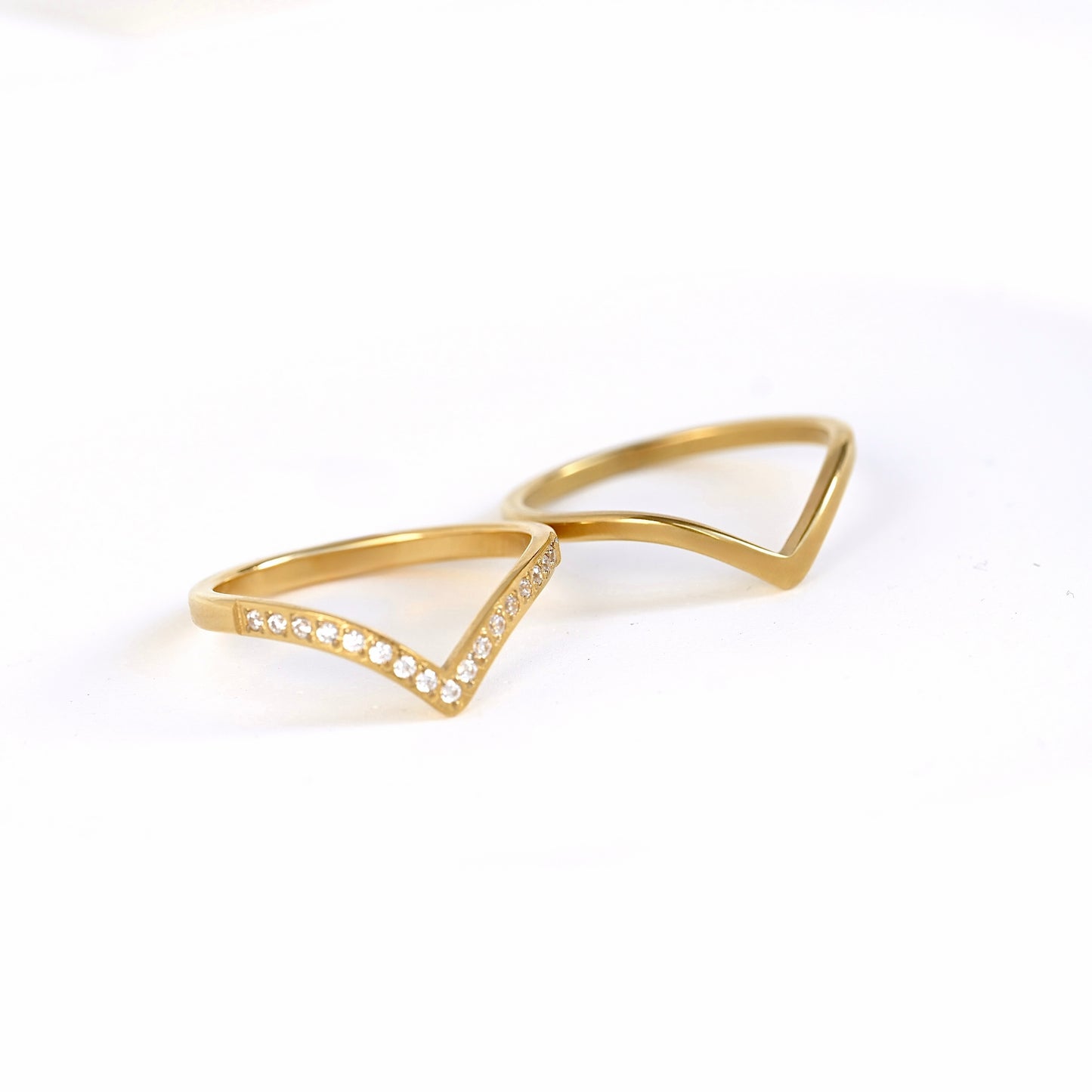A gold geometric ring featuring an open triangular design with a row of small clear pavé stones on one side, displayed on a clean white background.