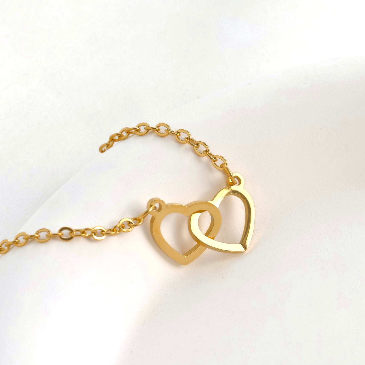 Gold heart duo bracelet with cable chain on a white background