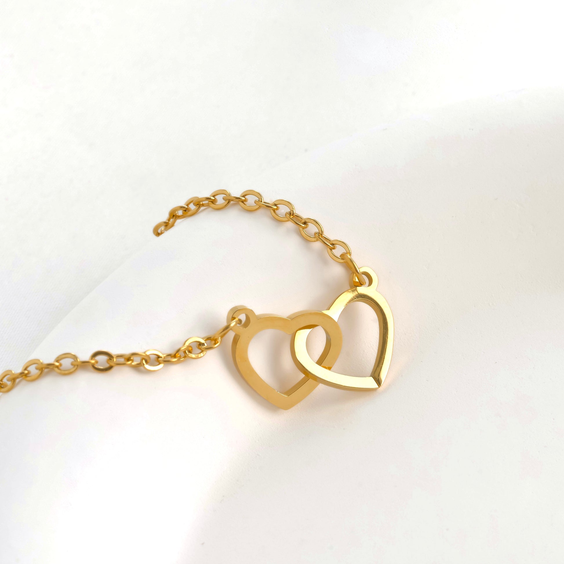 Gold heart duo bracelet with cable chain on a white background