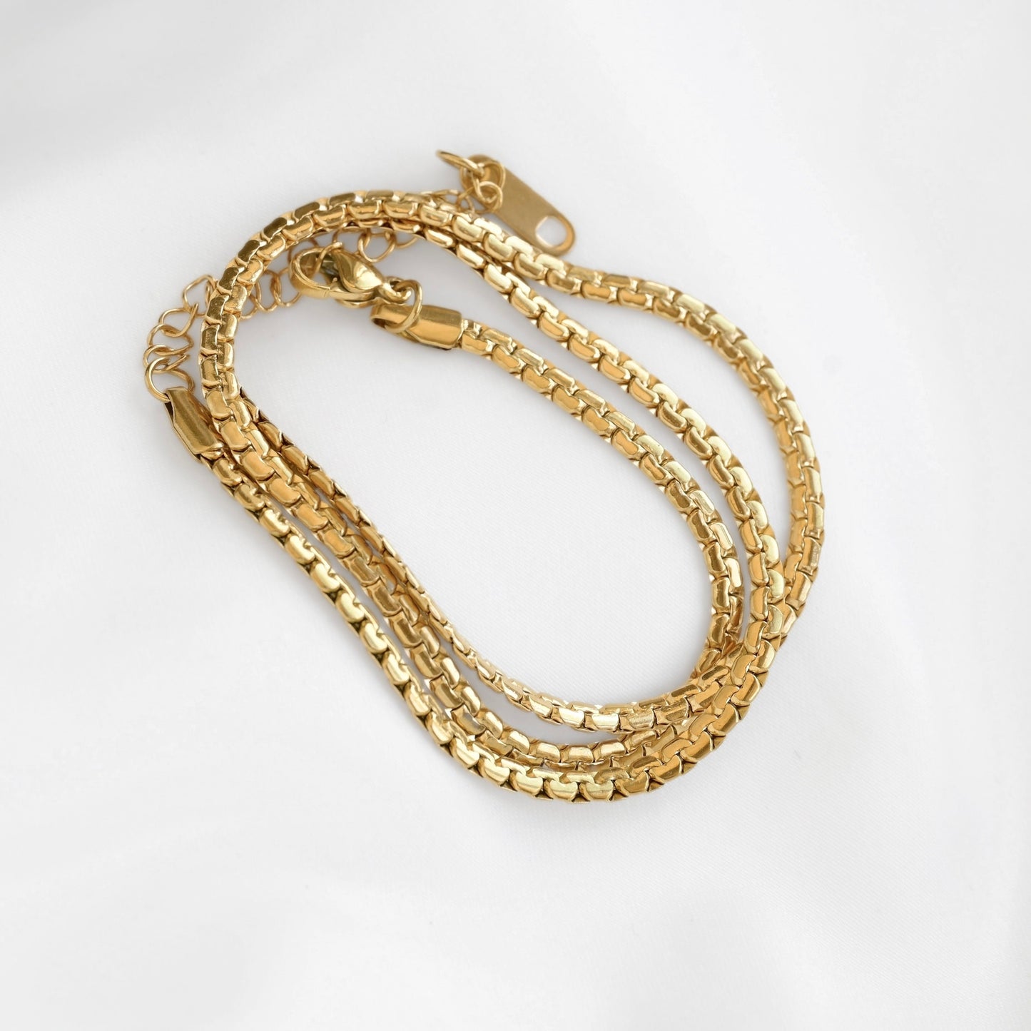 A gold-colored  chain necklace with a lobster clasp, displayed on a clean white background.