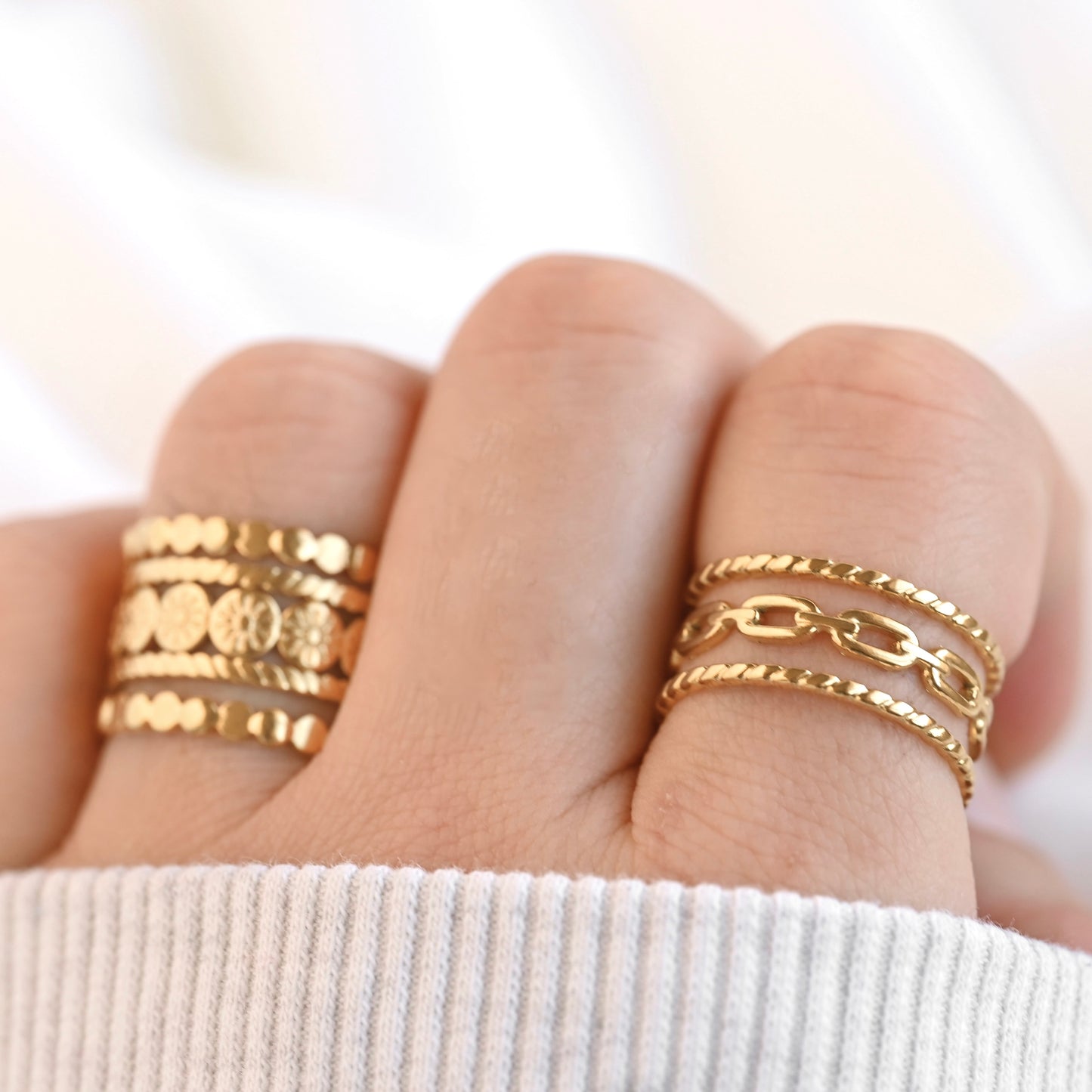 Resizable gold rings on a finger against a white background