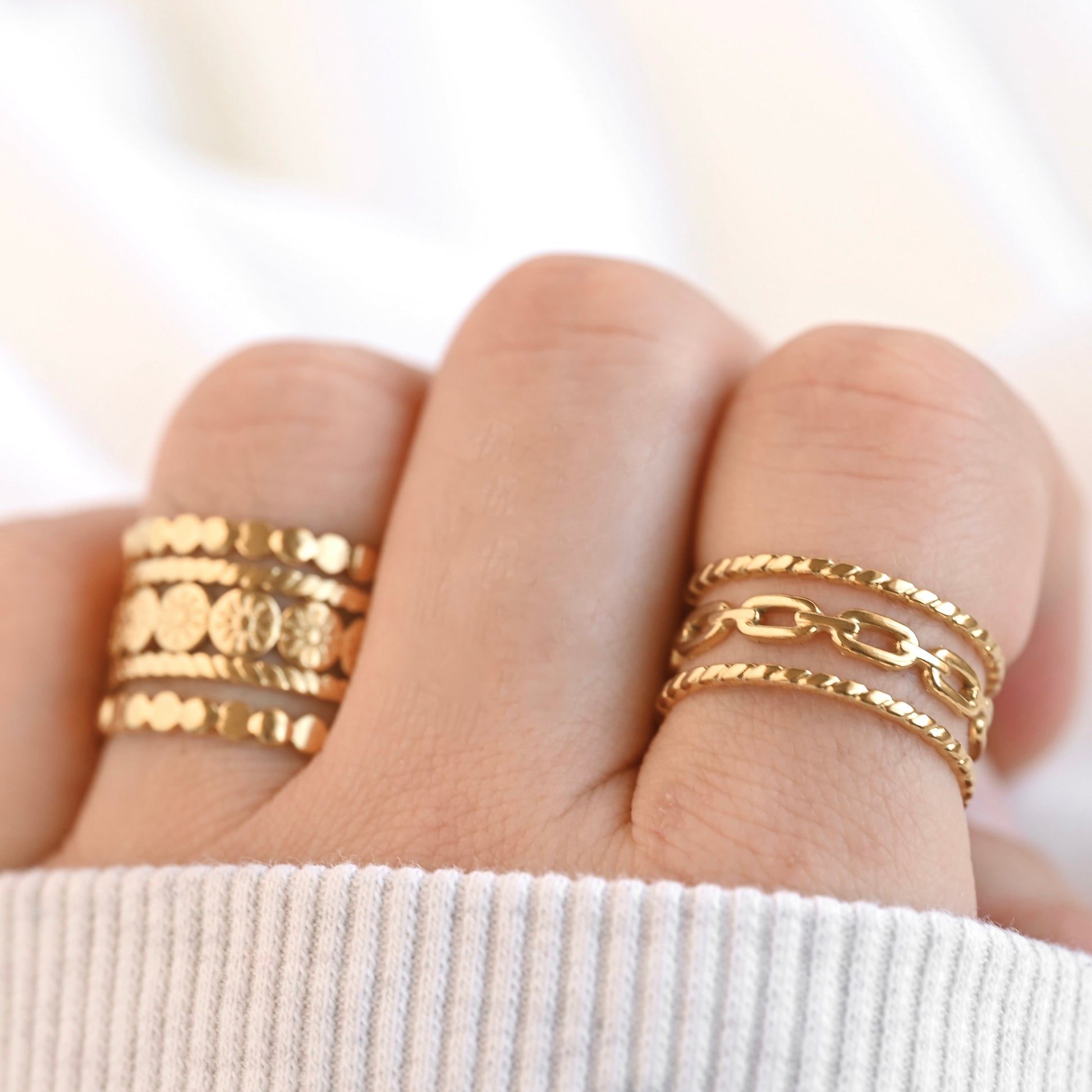 Resizable gold rings on a finger against a white background