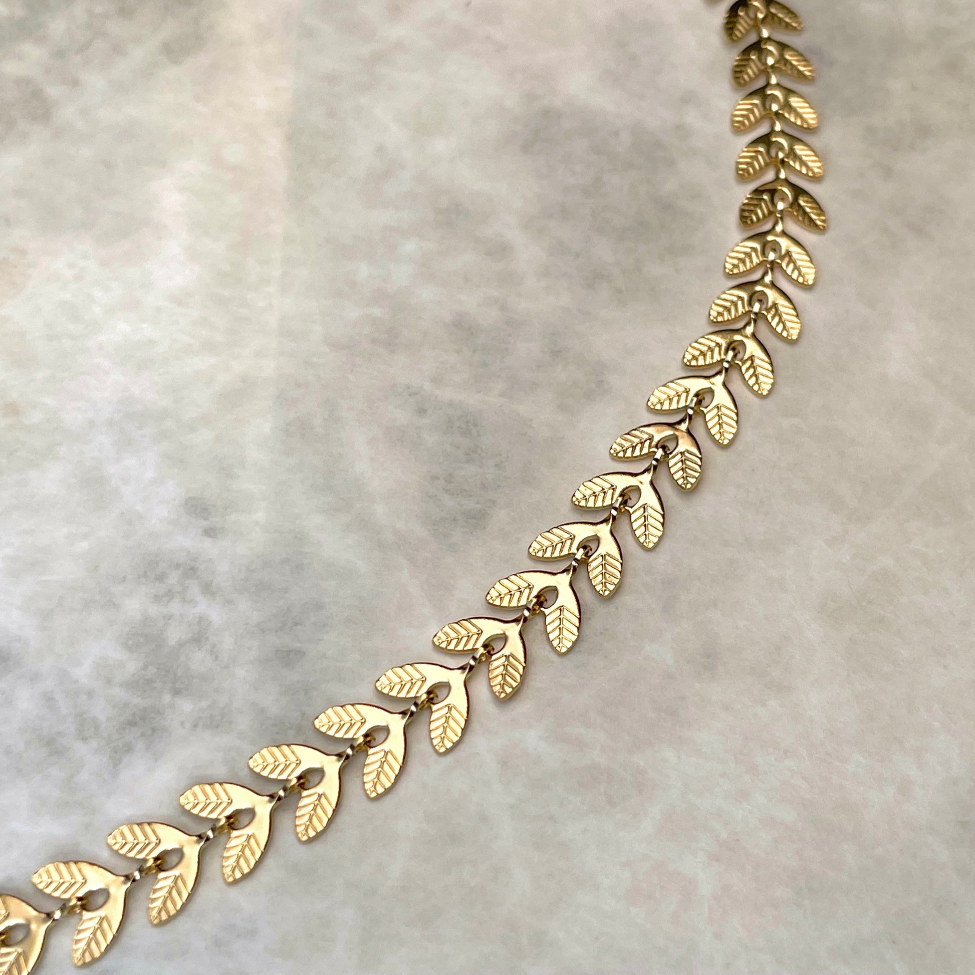 Close-up view of gold leaf links on a light gray background