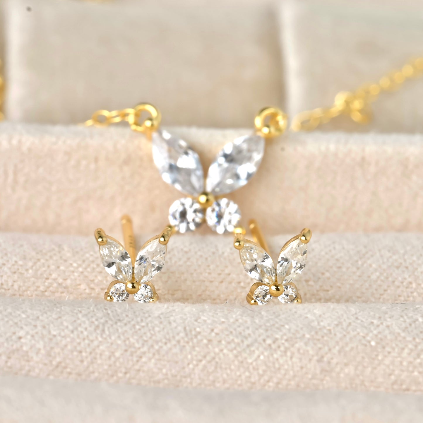 Diamond butterfly jewelry set with gold and clear stones on a beige background