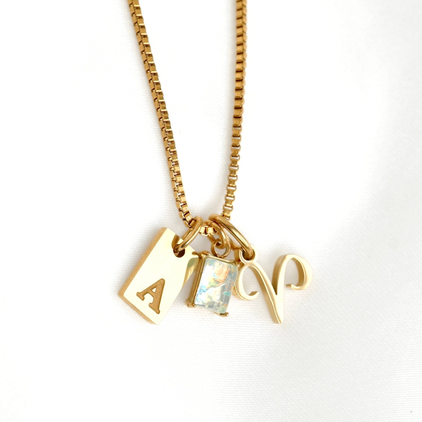 Gold necklace with three charms on a white background