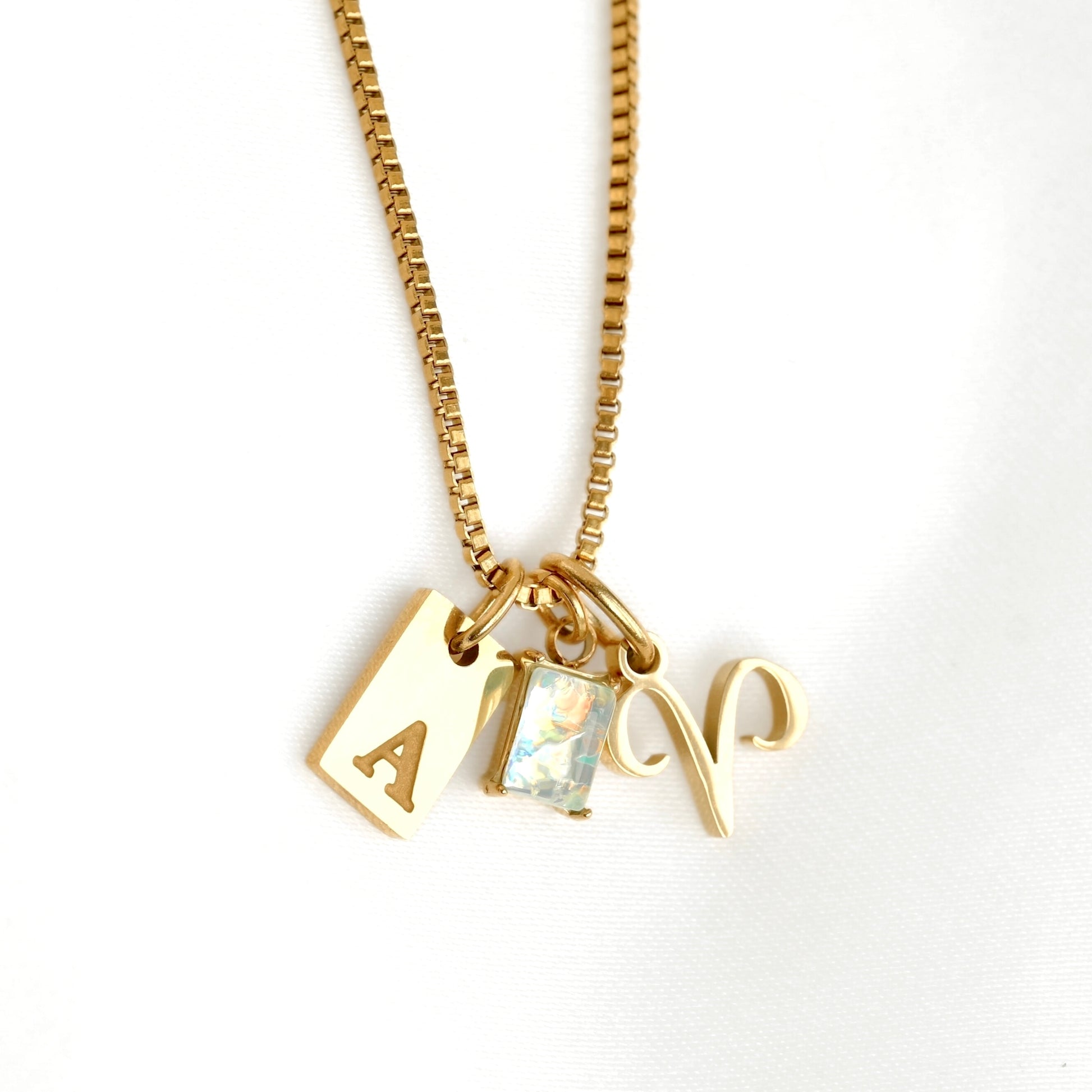 Gold necklace with three charms on a white background