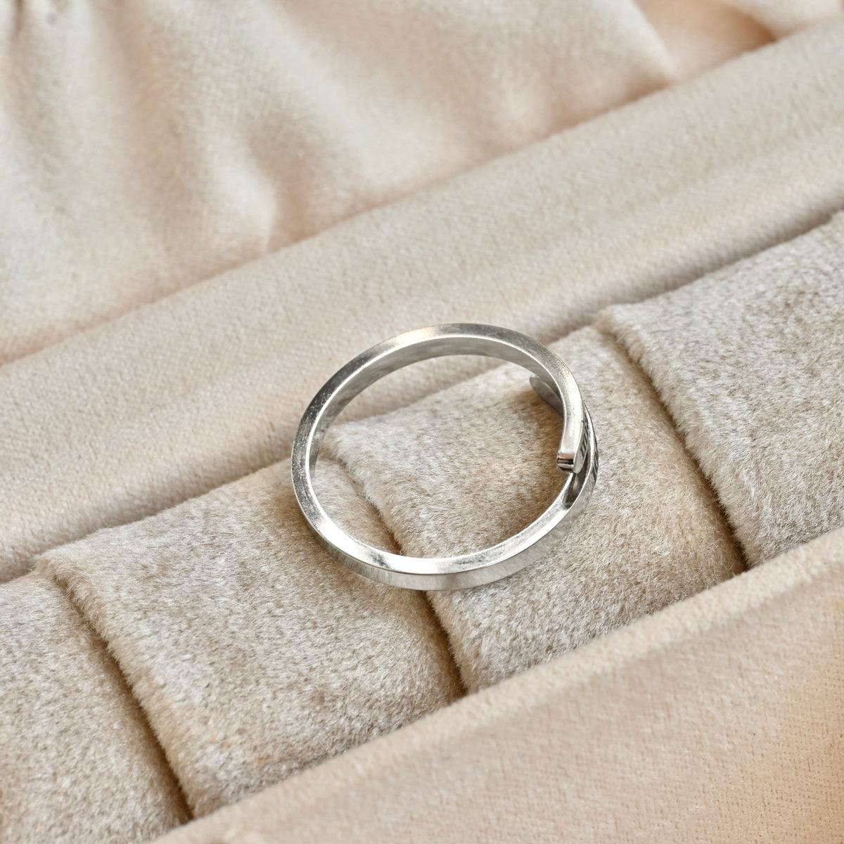 Dainty silver wrap ring on a beige fabric surface