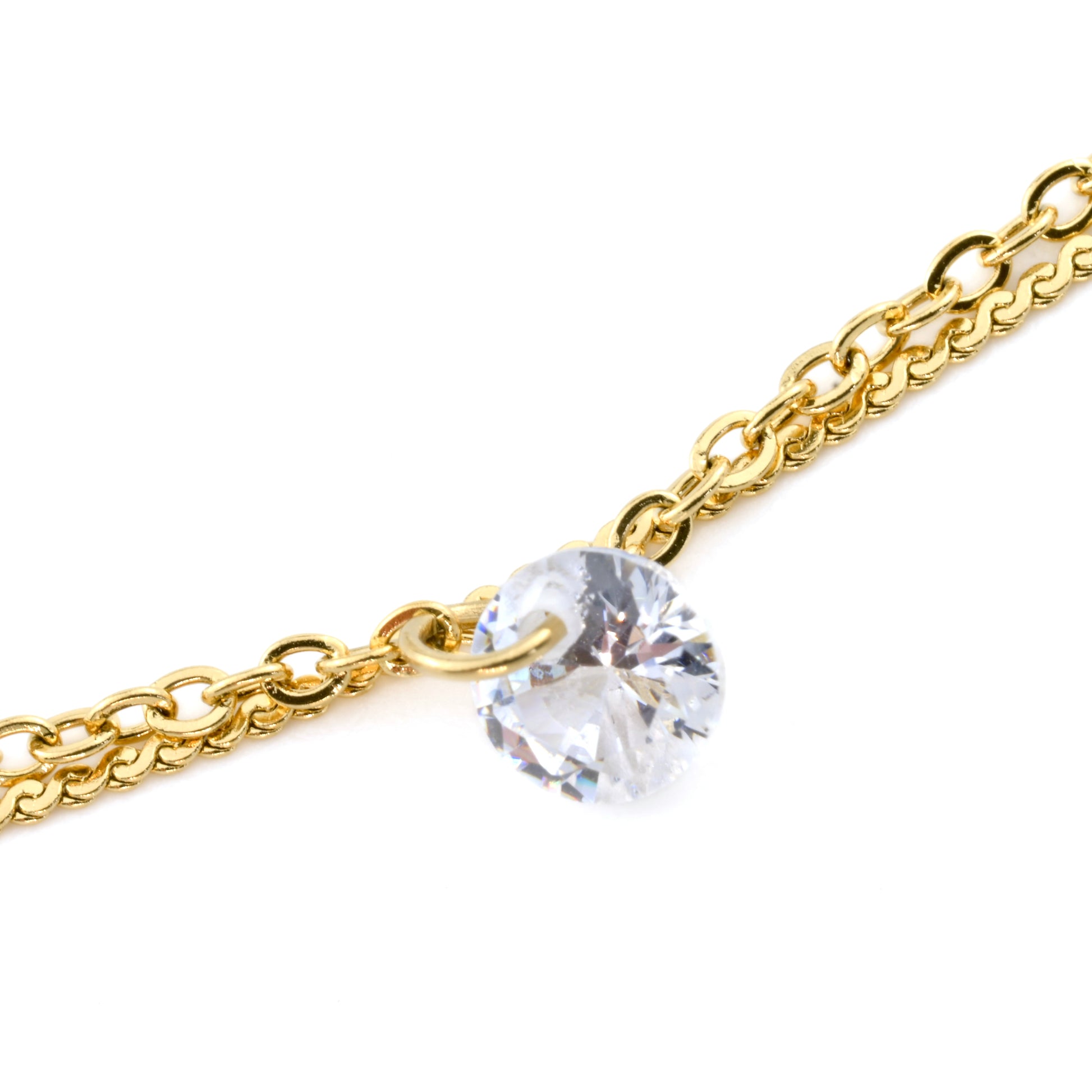 Close-up view of gold anklet's clear stone charm