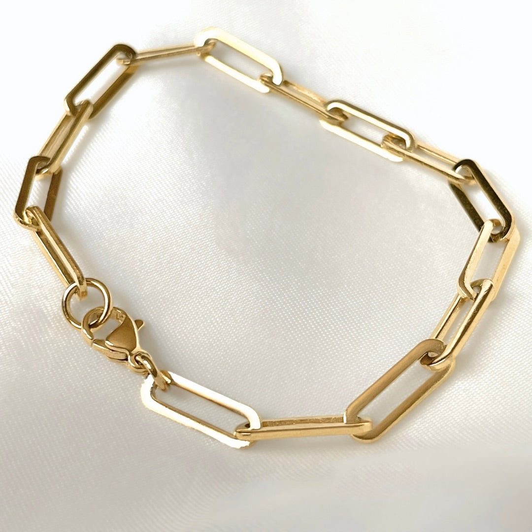 Close-up view of gold chunky paperclip chain bracelet on a white background