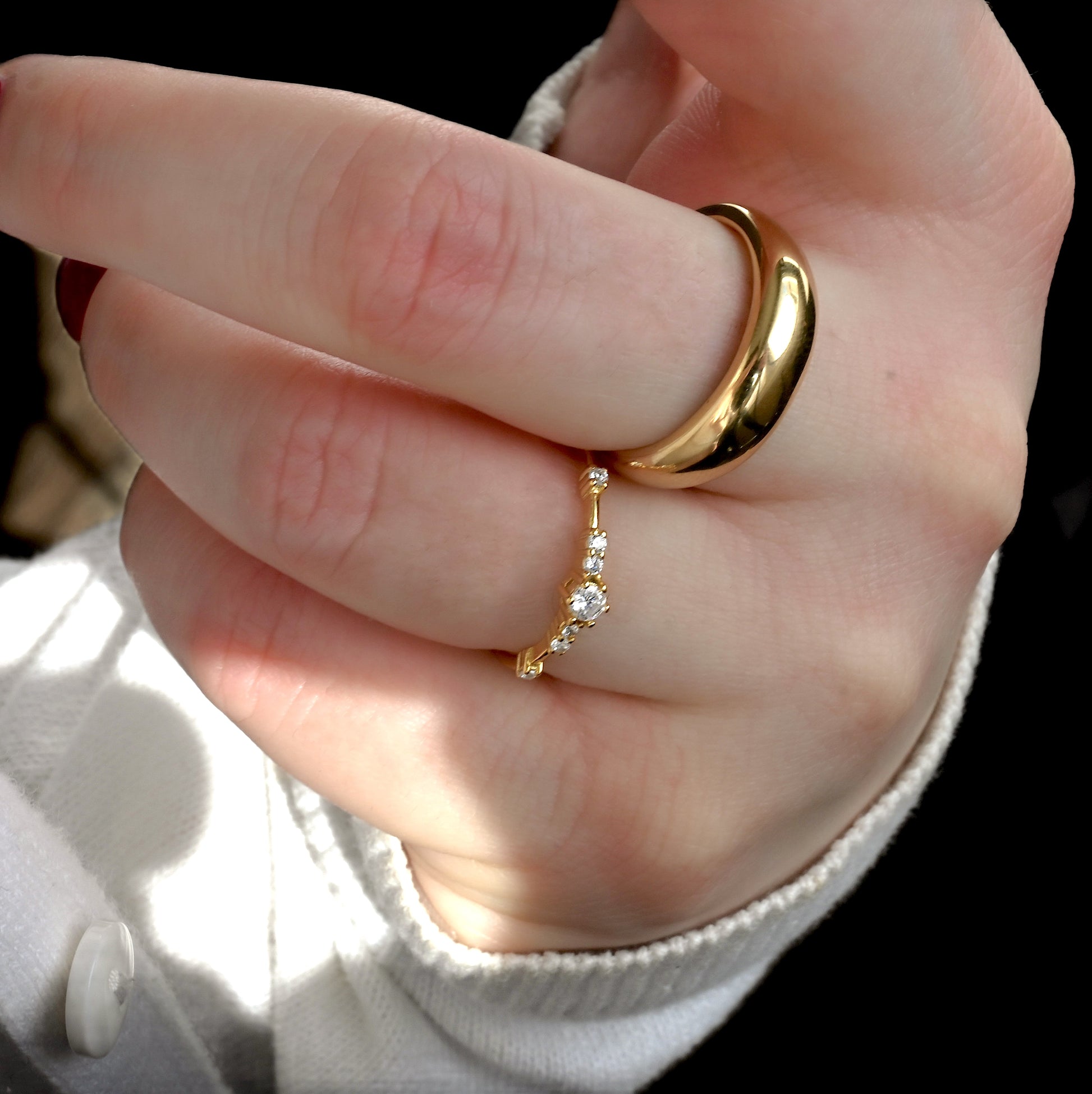Hand wearing two gold rings with a blurred background