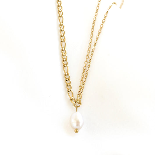 A gold double-strand necklace featuring a figaro chain and a delicate cable chain, both ending in a small gold bead that holds a white baroque pearl pendant, shown on a plain white background.
