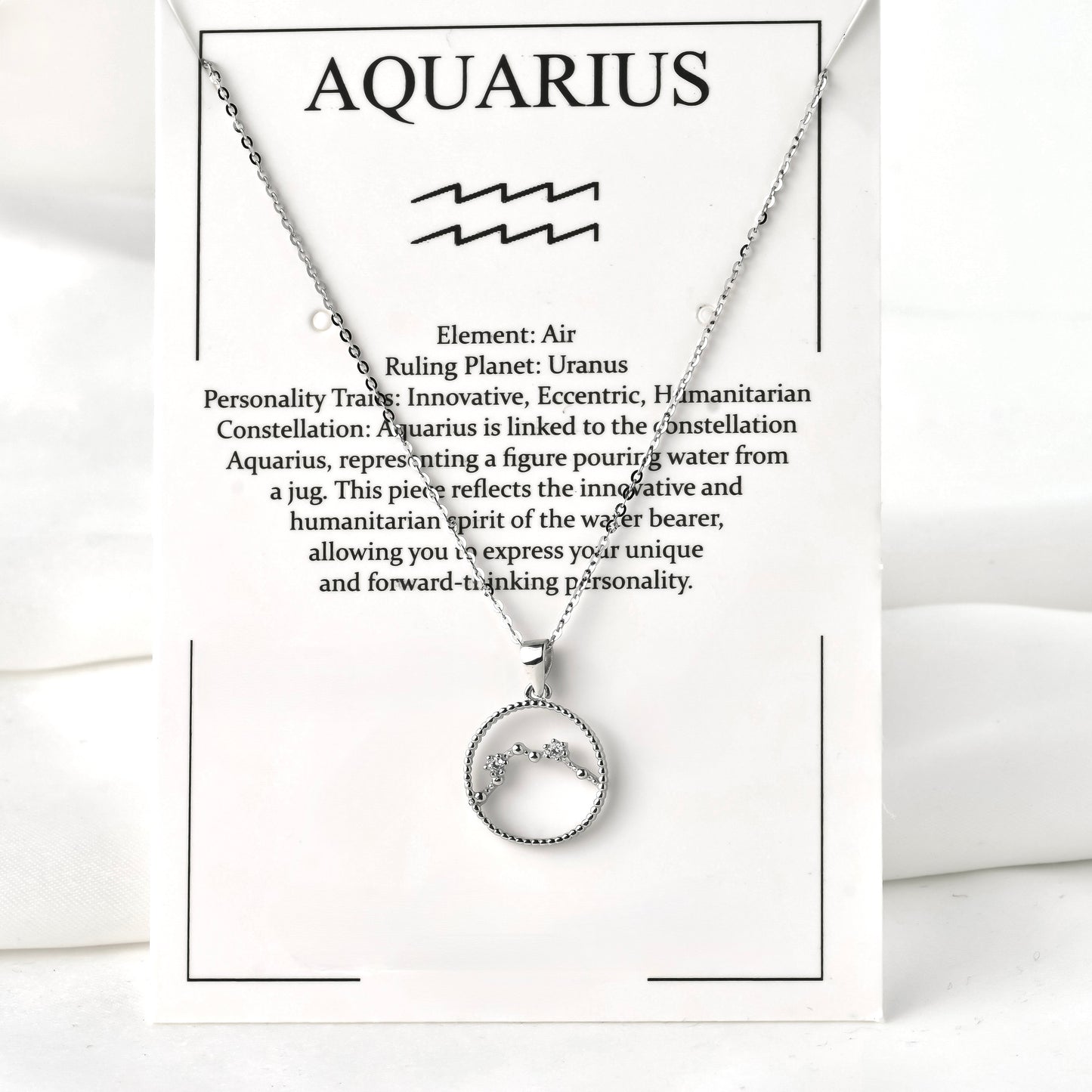 Silver necklace with Aquarius zodiac symbol on a white jewelry card with text