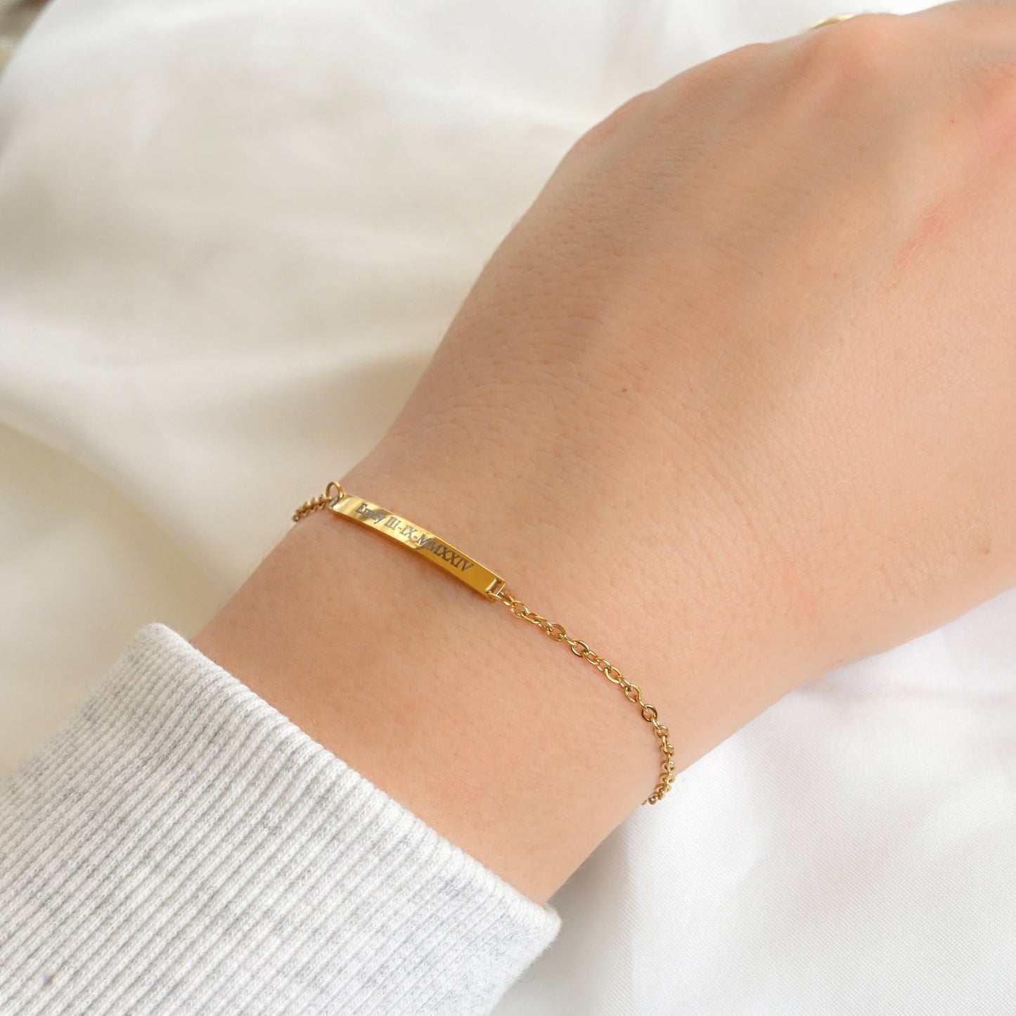 Gold bracelet on a person's wrist with a white background