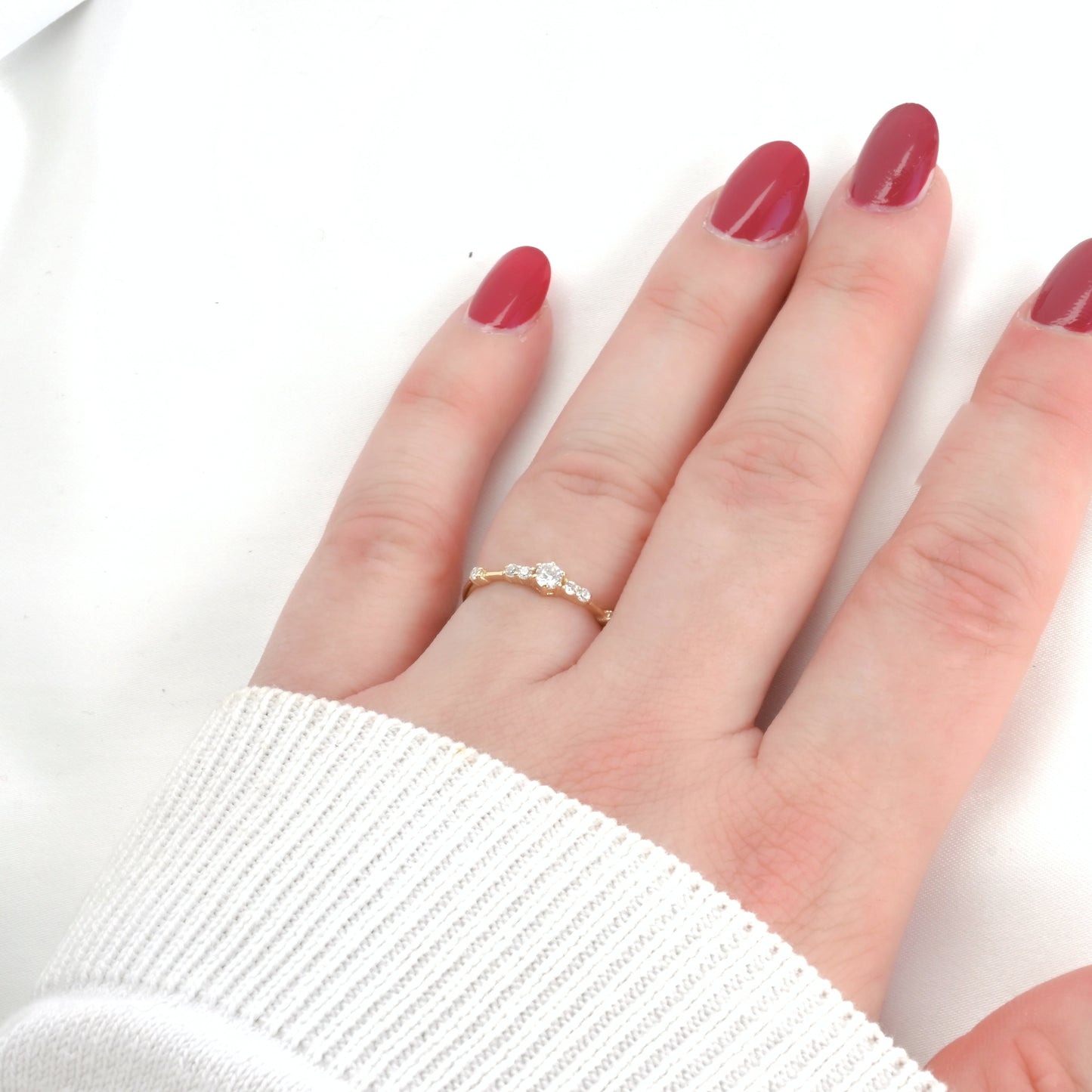 Hand wearing a gold ring with cz cluster on a white background