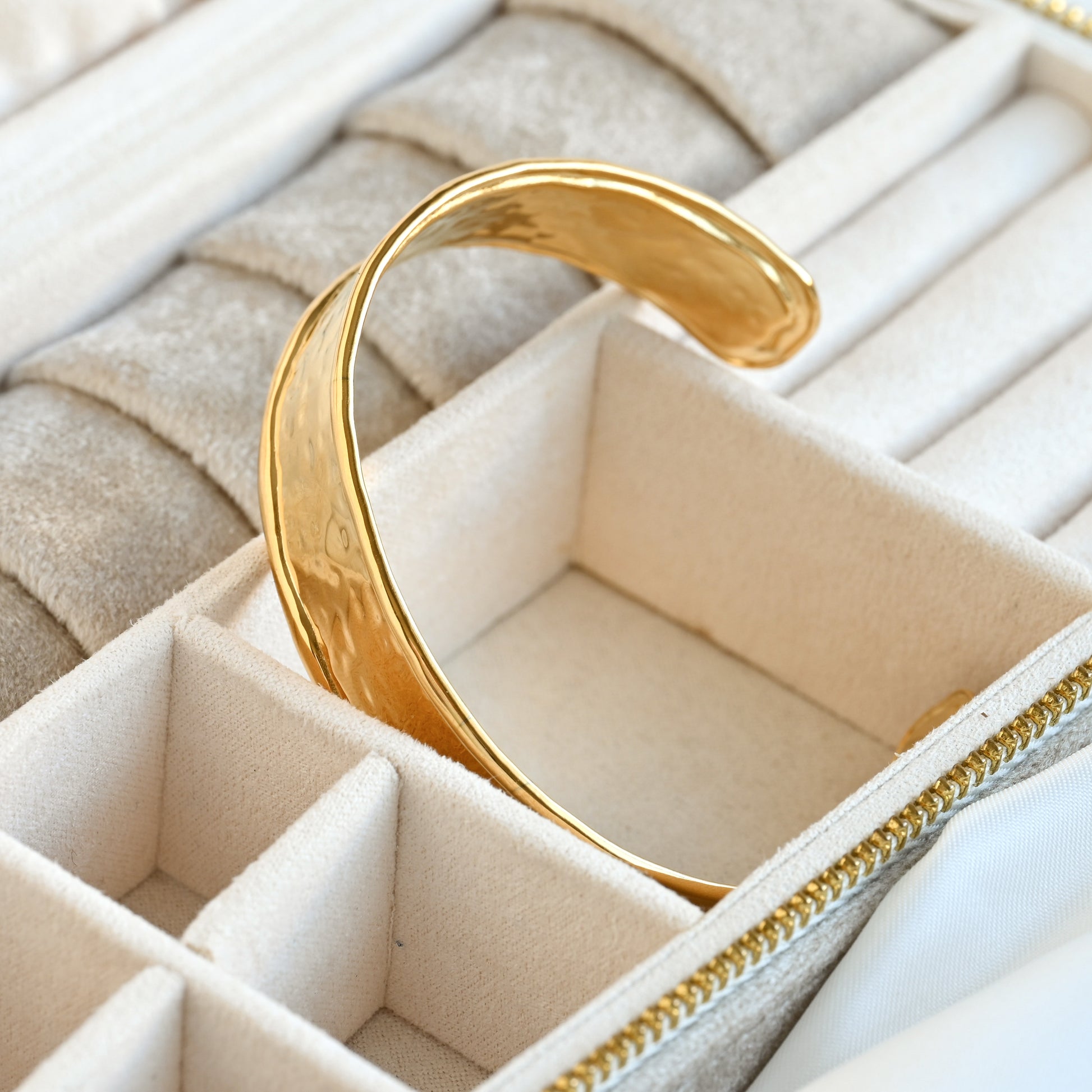 Gold  cuff bracelet in a jewelry box with a beige interior