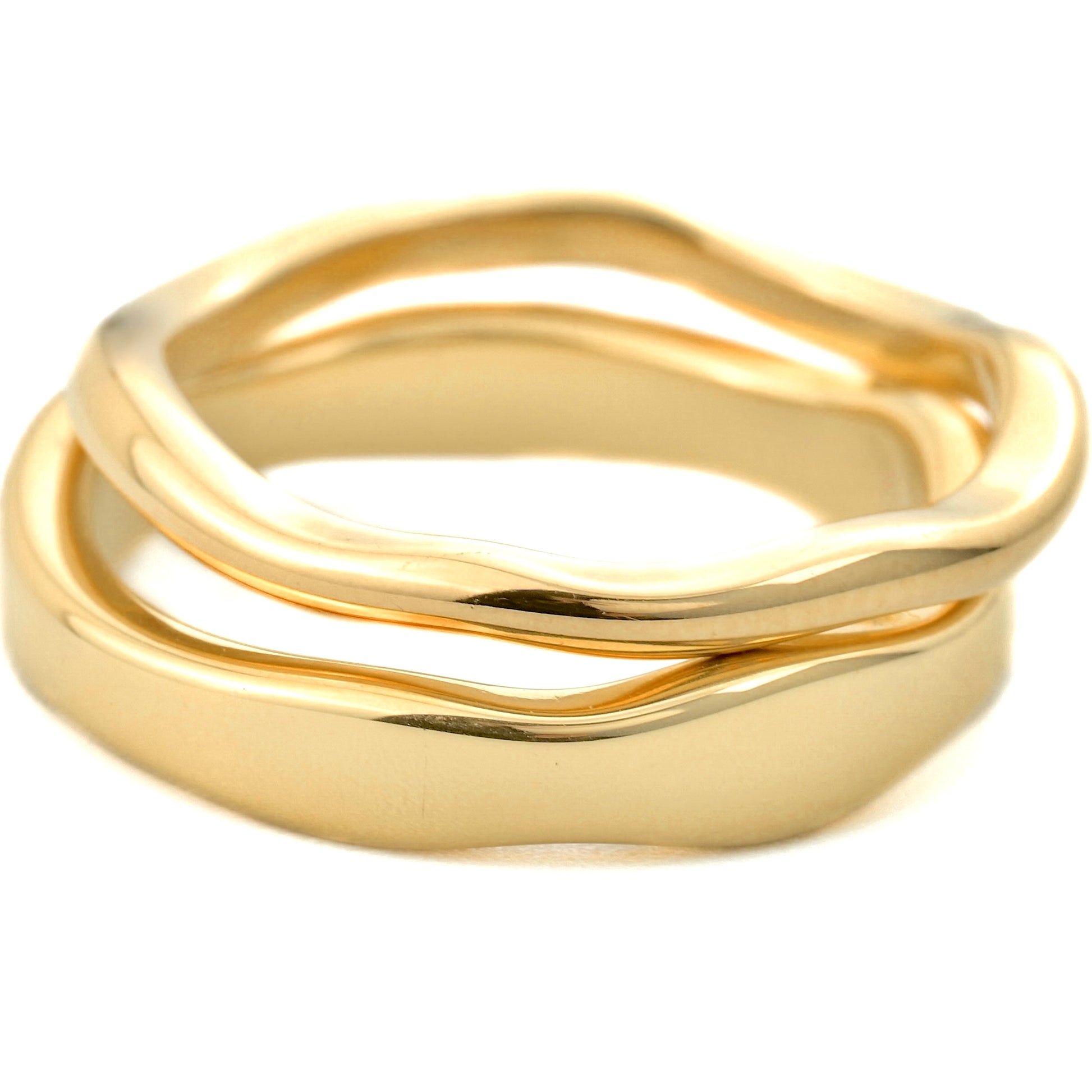 Ultra close-up view gold ring set with a wavy design stacked on a white background