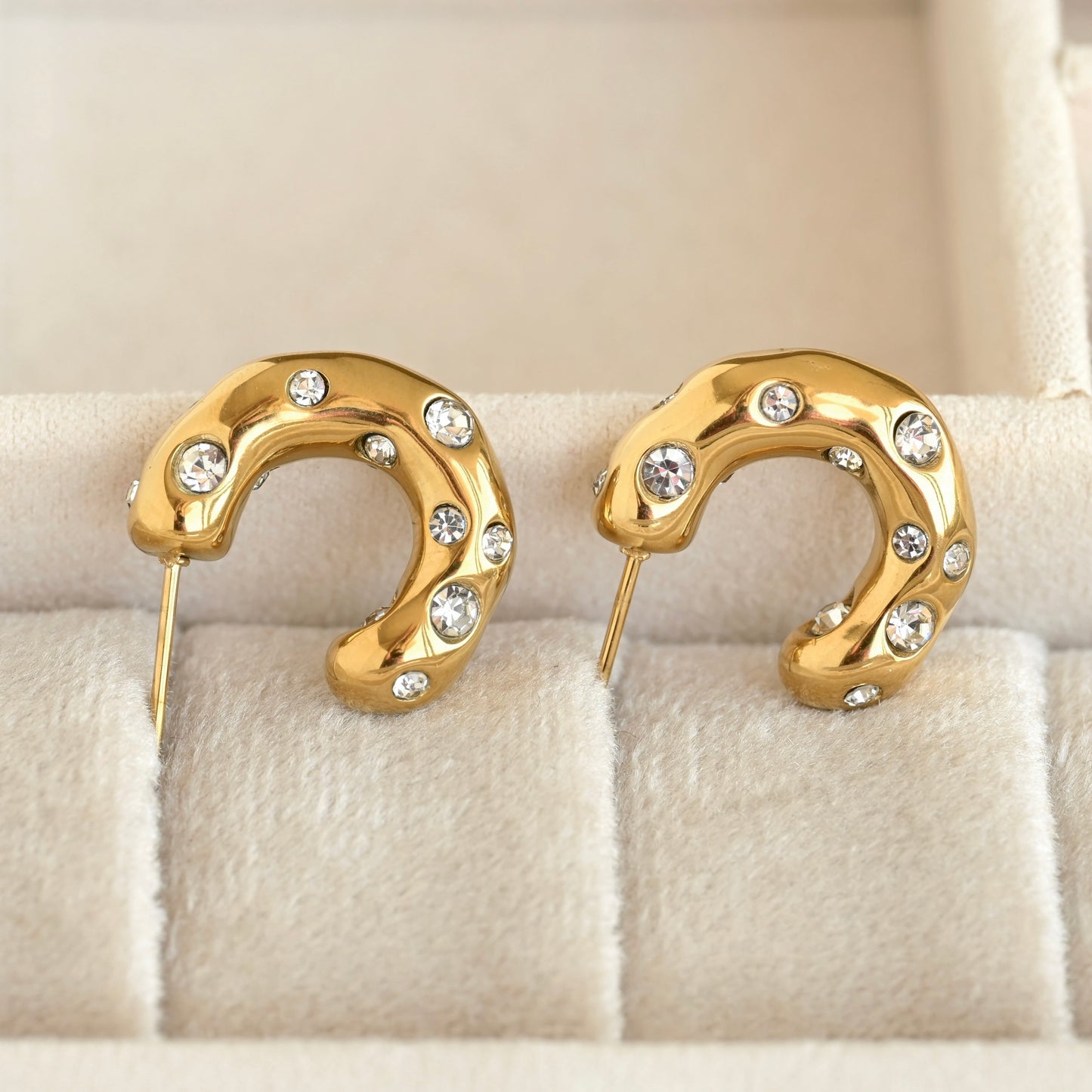 Gold organic shaped thick hoop earrings with clear CZ stones and posts in a beige jewelry box