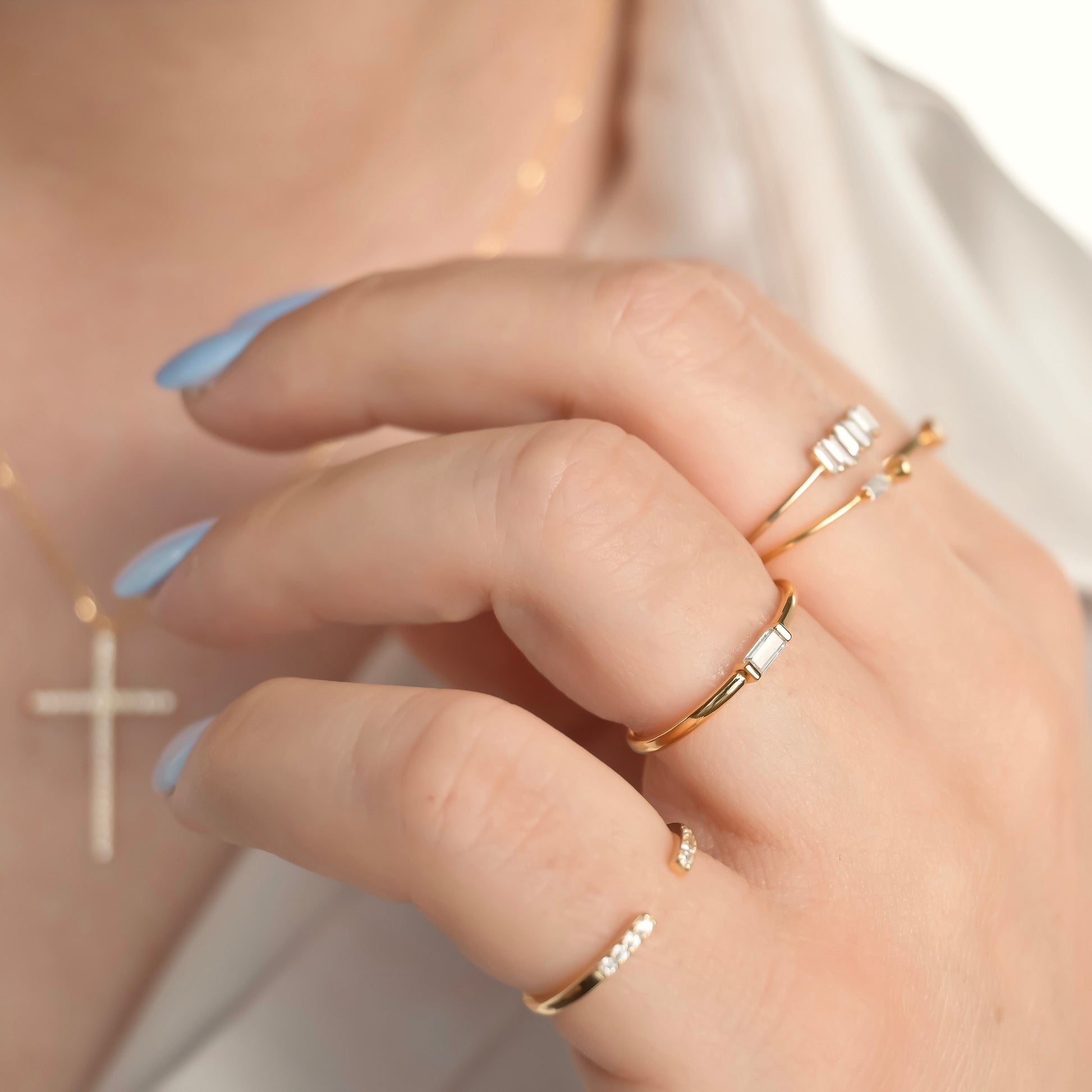 Close-up of a hand wearing multiple gold rings with a blurred background