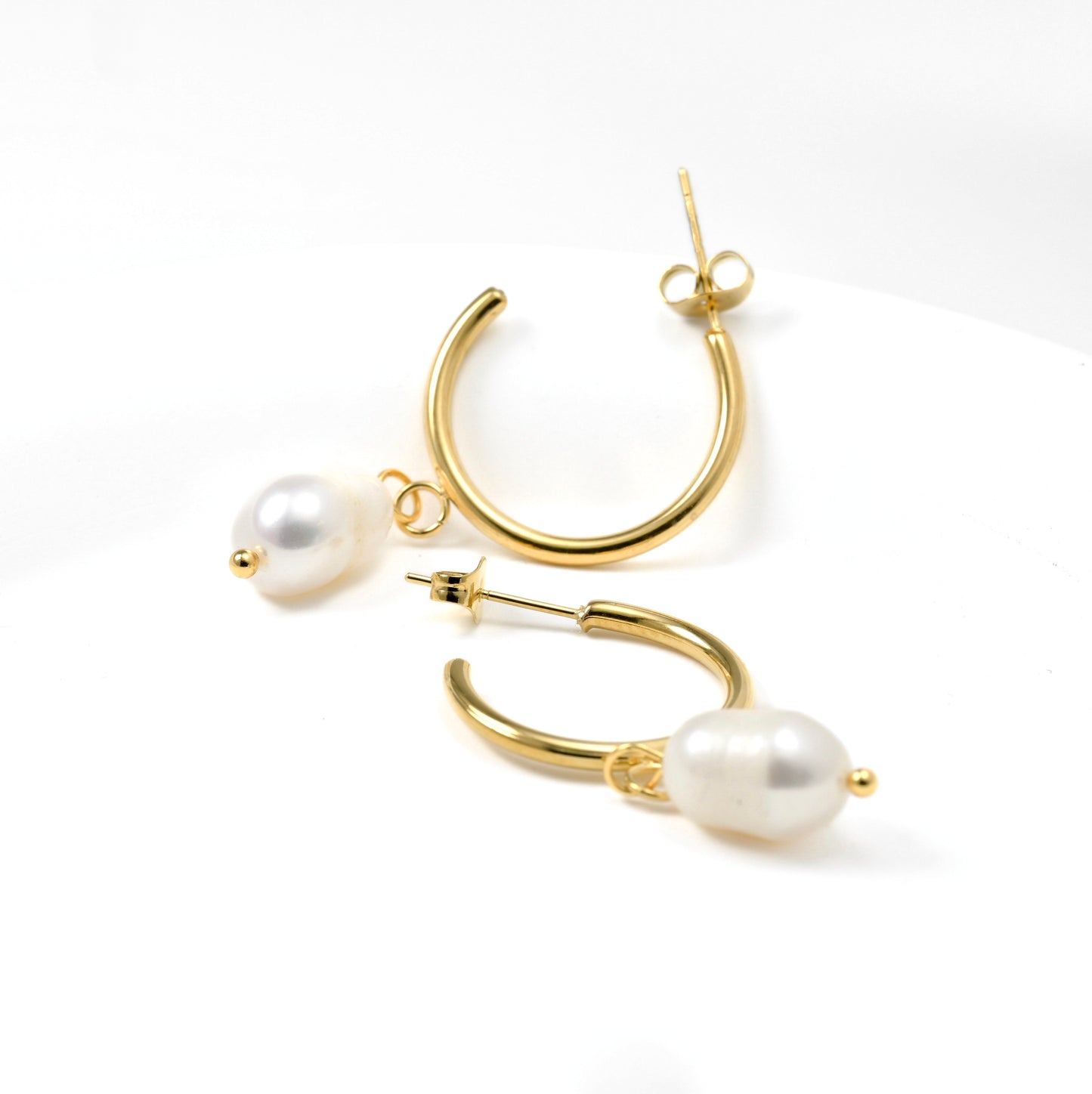 Gold hoop earrings with pearl accents on a white background