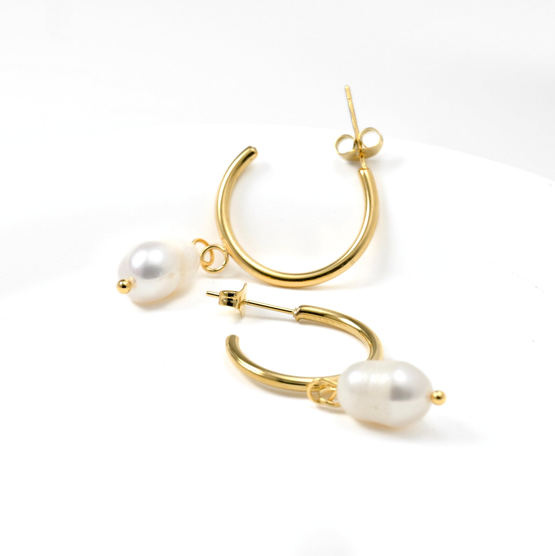 Gold hoop earrings with pearl accents on a white background