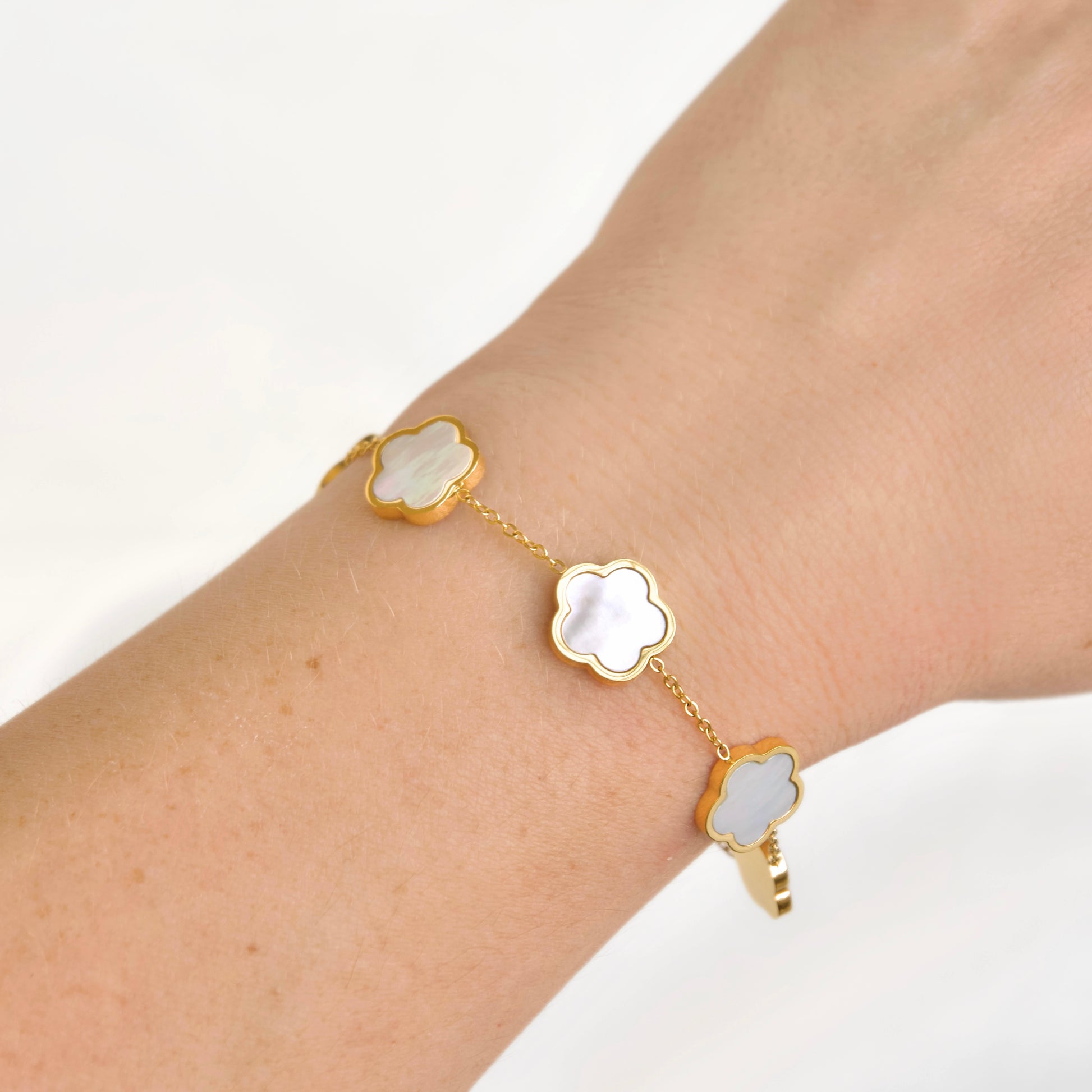 A delicate gold chain bracelet with three cloud-shaped mother-of-pearl charms, shown worn on a person's wrist against a clean white background.