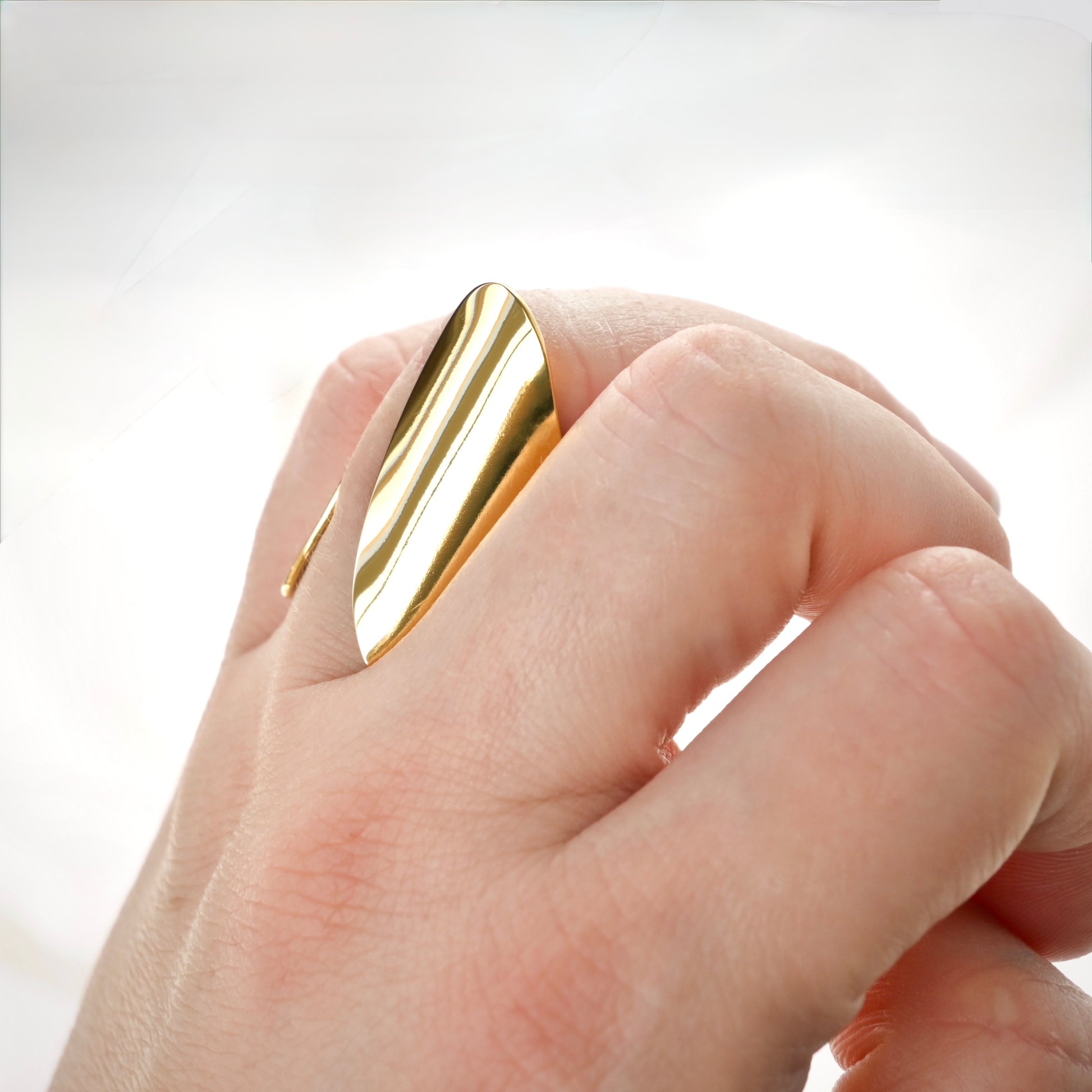 Modern Gold ring on a person's finger against a white background