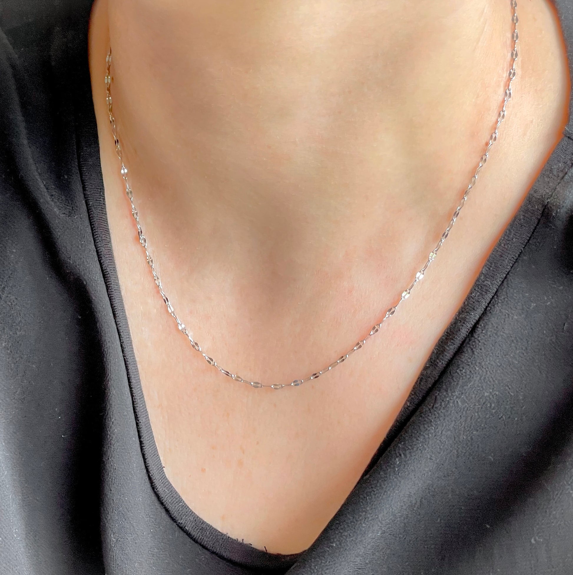 Silver chain necklace on a person wearing a black top