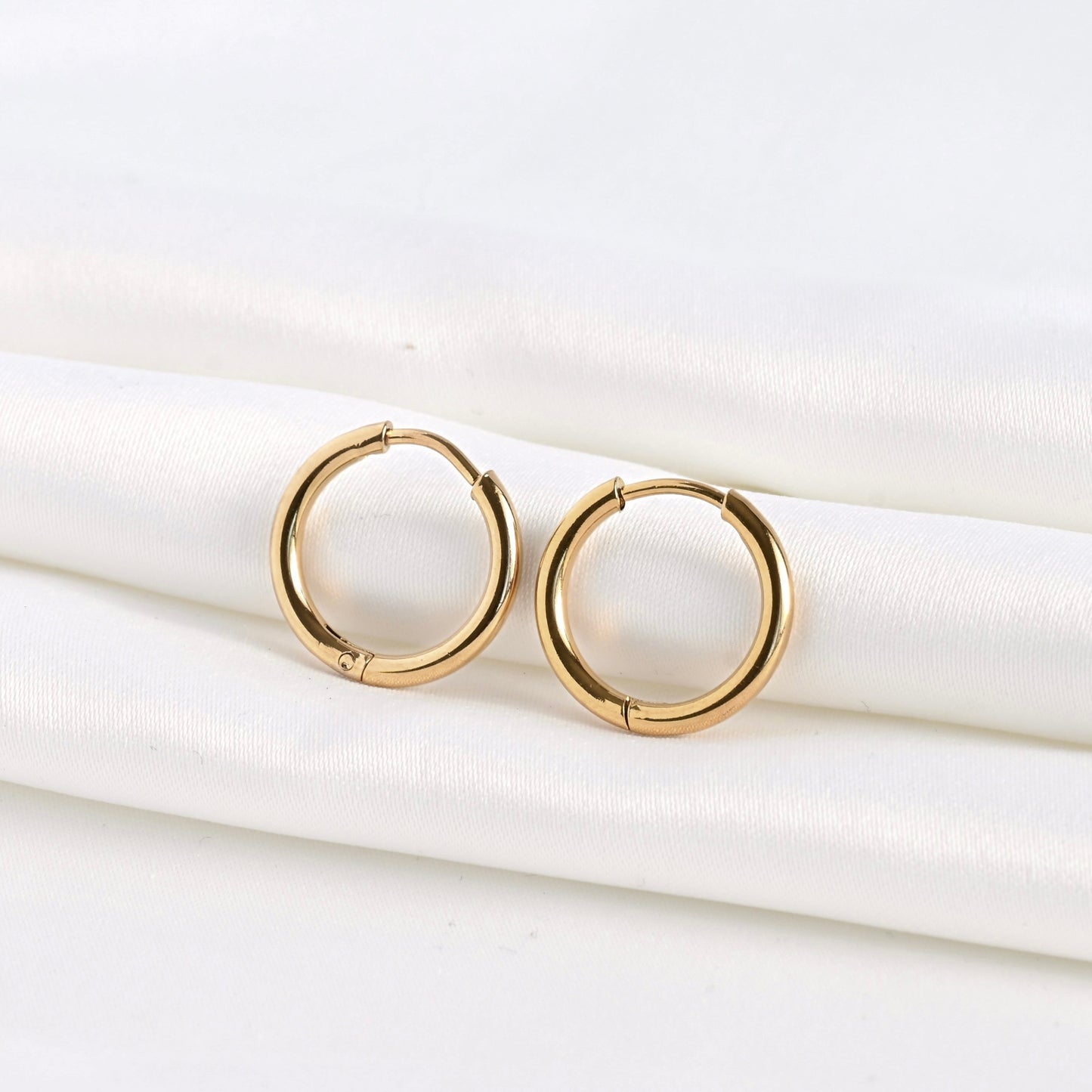 Front view of gold sleeper huggies on a white fabric background