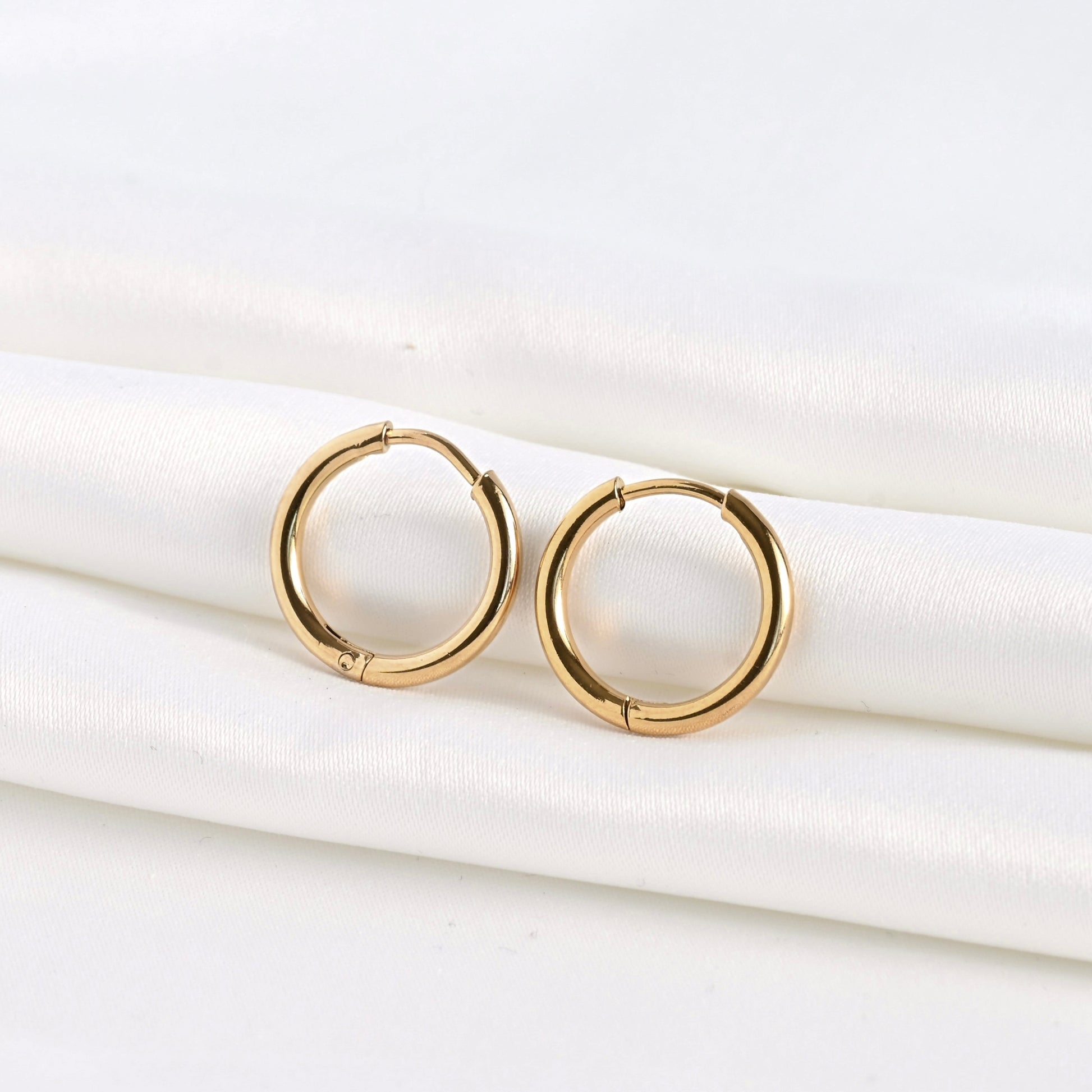 Front view of gold sleeper huggies on a white fabric background