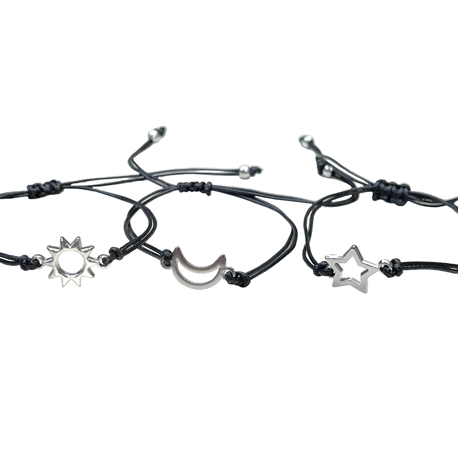 Three black cord bracelets with silver sun, moon, and star charms and sliding knots on a white background