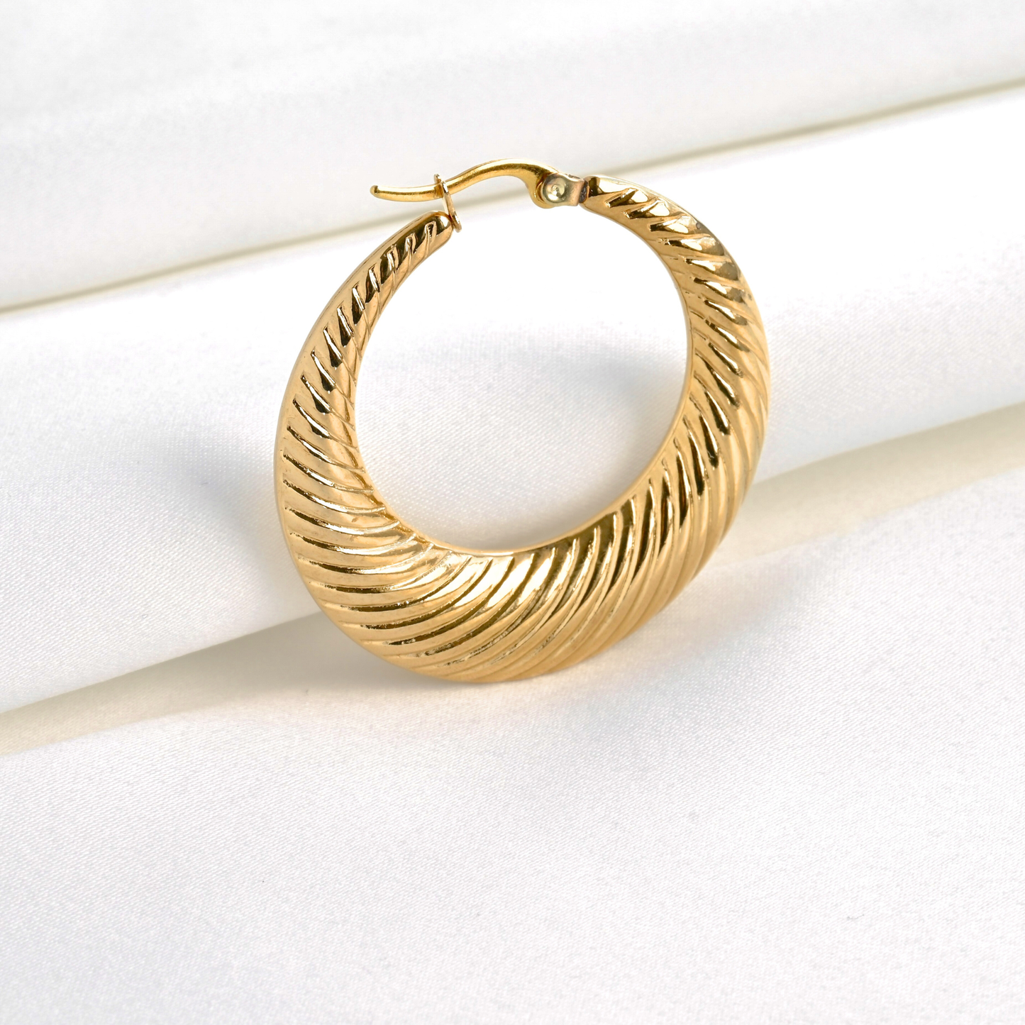 Close up view of gold croissant hoop earrings with a latch-back closure on a white background